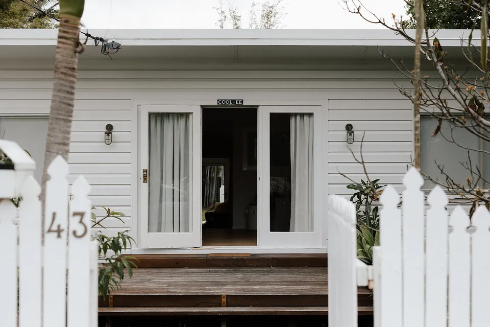 The white weatherboard entrance, timber steps and tropical planting at Grounds of Cabarita in Cabarita Beach, NSW, for an Elopement Collective elopement. Photo by Bulb Creative.