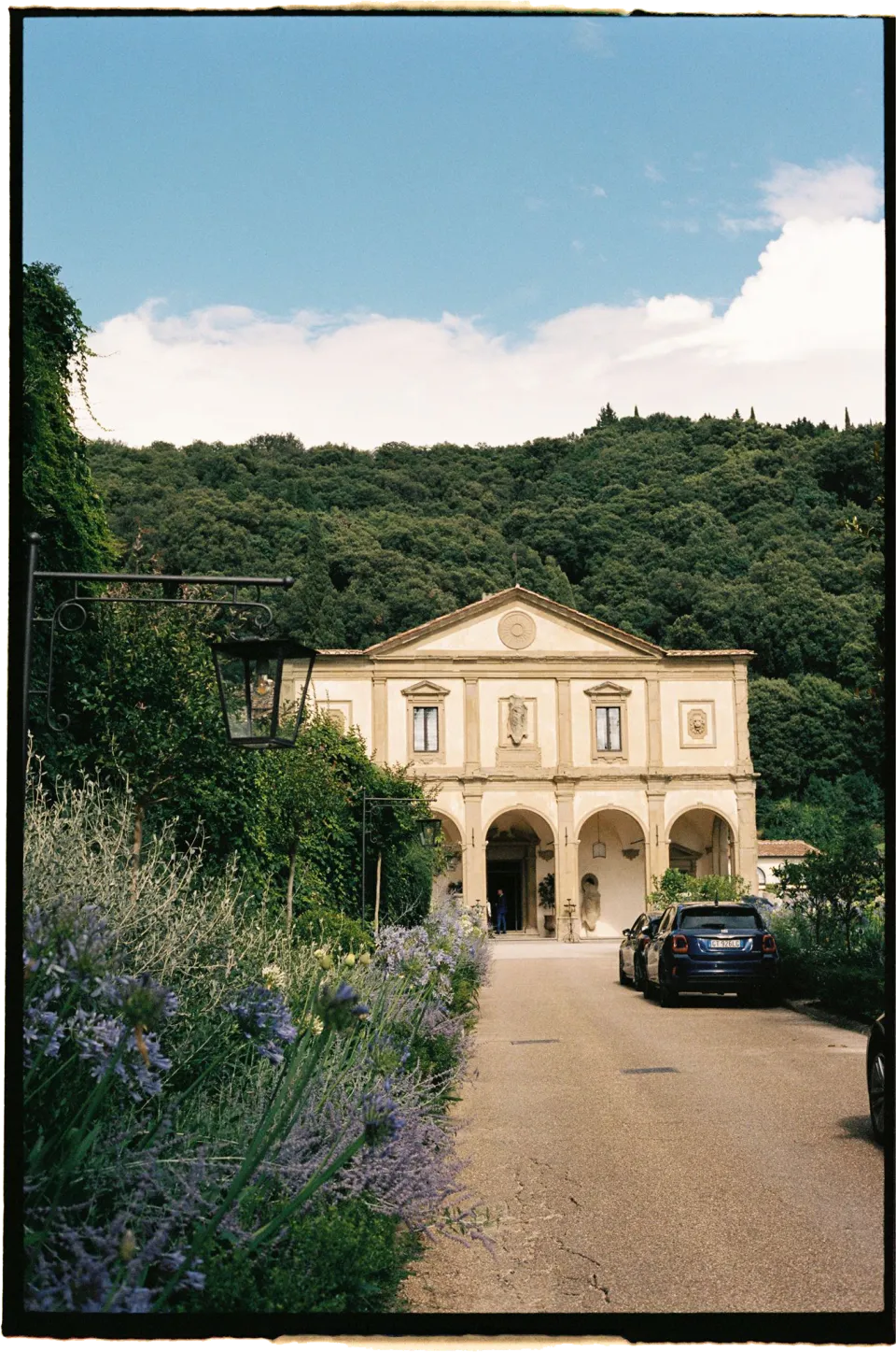 Villa San Michele’s facade and arched loggia at the end of a garden path, at Villa San Michele in Fiesole above Florence, Tuscany, Italy, for an Elopement Collective elopement. Film photograph by Khara from House of Lucie.