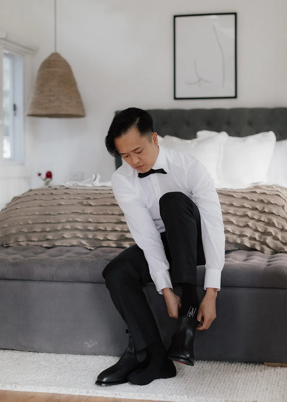 Jonathan pulling on a black boot before the ceremony. At Fig Tree Villa in Ewingsdale, Byron Bay, for an Elopement Collective elopement. Photograph by Bulb Creative.