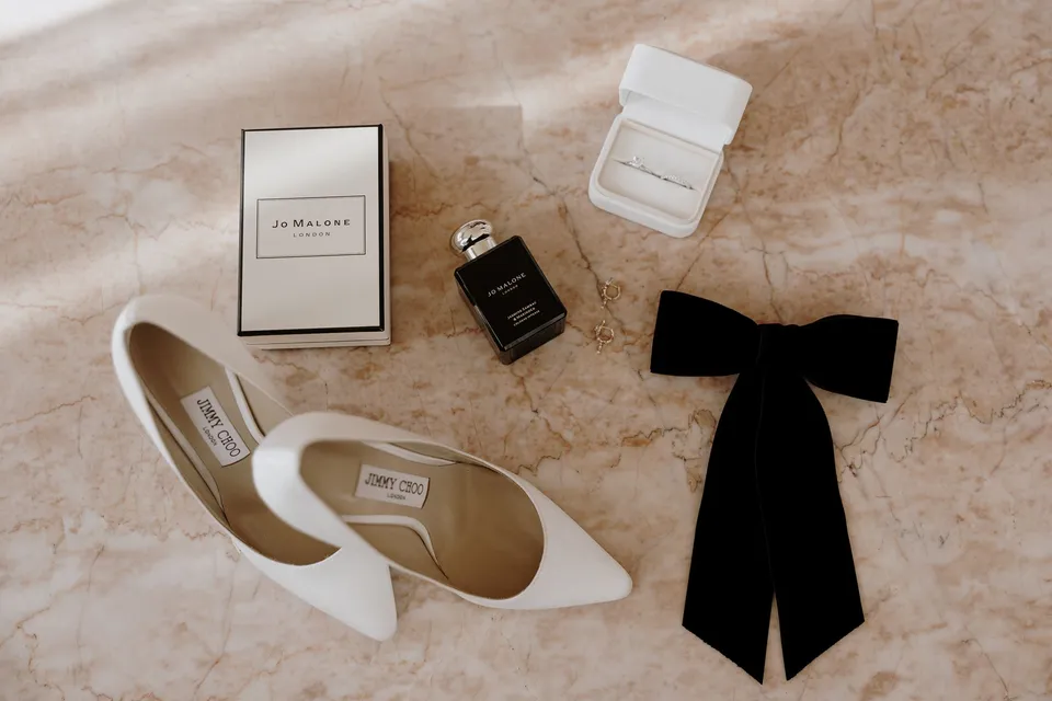 White pointed heels, perfume, a jewellery box and a black ribbon bow on pink stone, during Danielle and Adam’s Elopement Collective elopement at The Calile Hotel in Fortitude Valley, Brisbane.