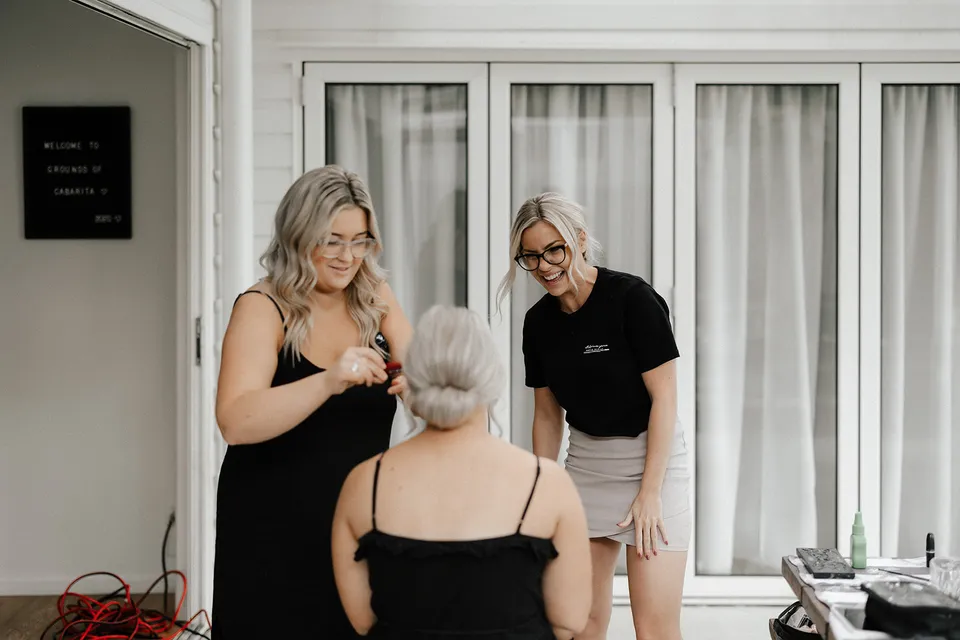 Three people chatting on the terrace during preparations, at Grounds of Cabarita in Cabarita Beach, NSW, for an Elopement Collective elopement. Photo by Bulb Creative.