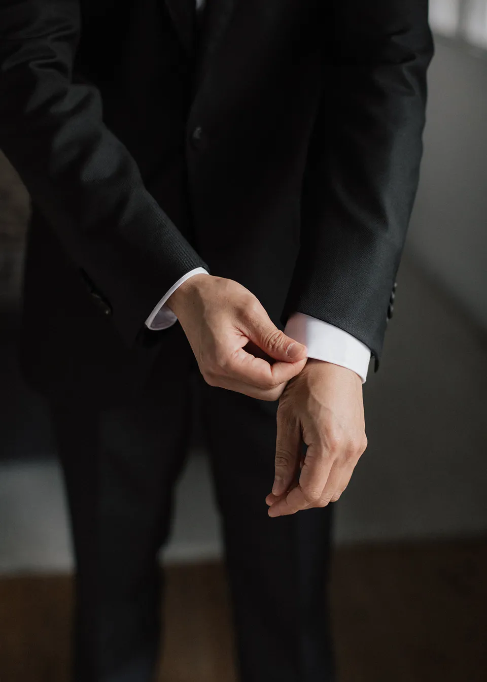 Jonathan adjusting the cuff of his white shirt. At Fig Tree Villa in Ewingsdale, Byron Bay, for an Elopement Collective elopement. Photograph by Bulb Creative.