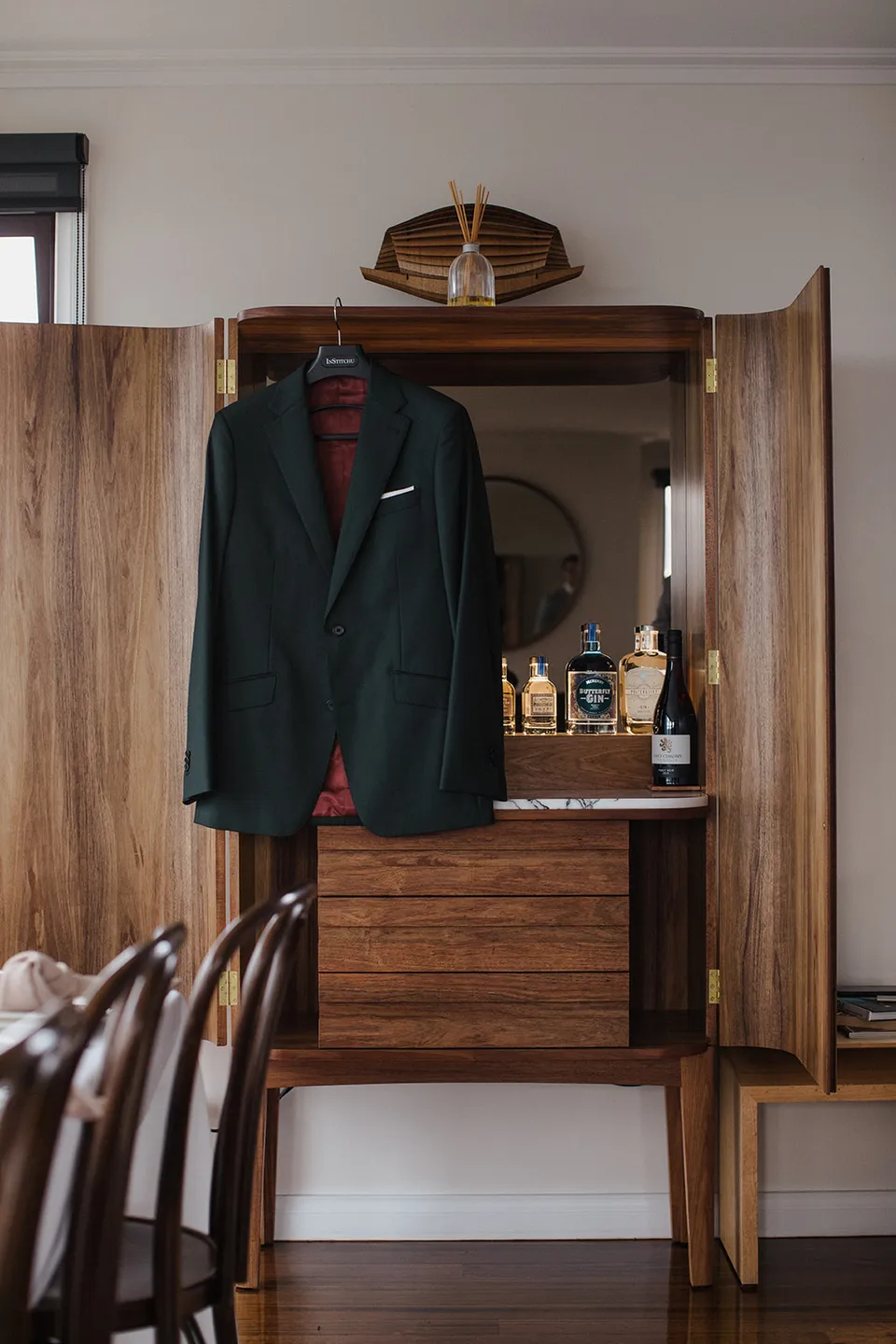 Ryan’s dark green suit hanging from a timber wardrobe inside The Keep. At The Keep on Tasmania’s east coast, for an Elopement Collective elopement. Photograph by Jenna Agius.