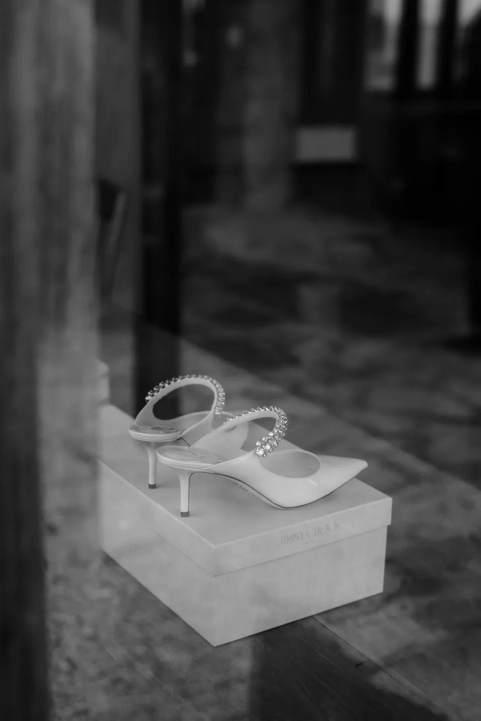 Black and white photograph of bridal shoes on their box in the stone courtyard, at Thalia Haven on the East Coast of Tasmania, Australia, for an Elopement Collective elopement. Photograph by Joey Willis.