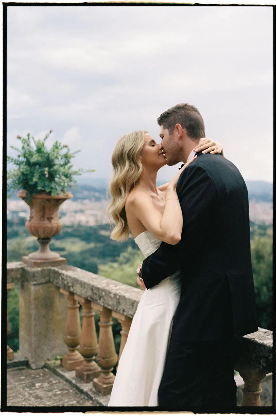 Holly and Matthew sharing a kiss beside the stone balustrade above Florence, at Villa San Michele in Fiesole above Florence, Tuscany, Italy, for an Elopement Collective elopement. Film photograph by Khara from House of Lucie.