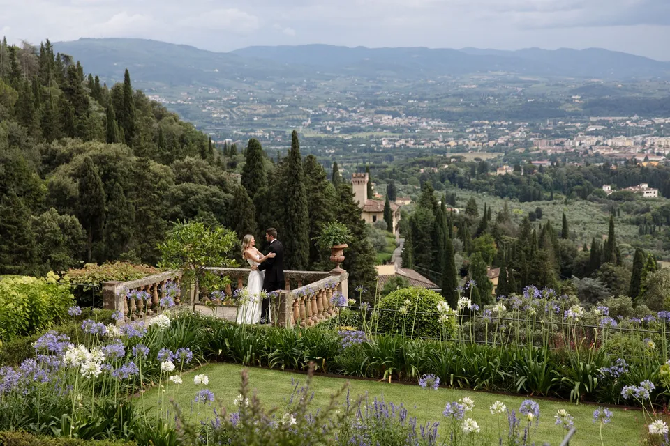 Holly and Matthew standing on the terrace amid the villa gardens, with Florence beyond, at Villa San Michele in Fiesole above Florence, Tuscany, Italy, for an Elopement Collective elopement. Digital photograph by Khara from House of Lucie.