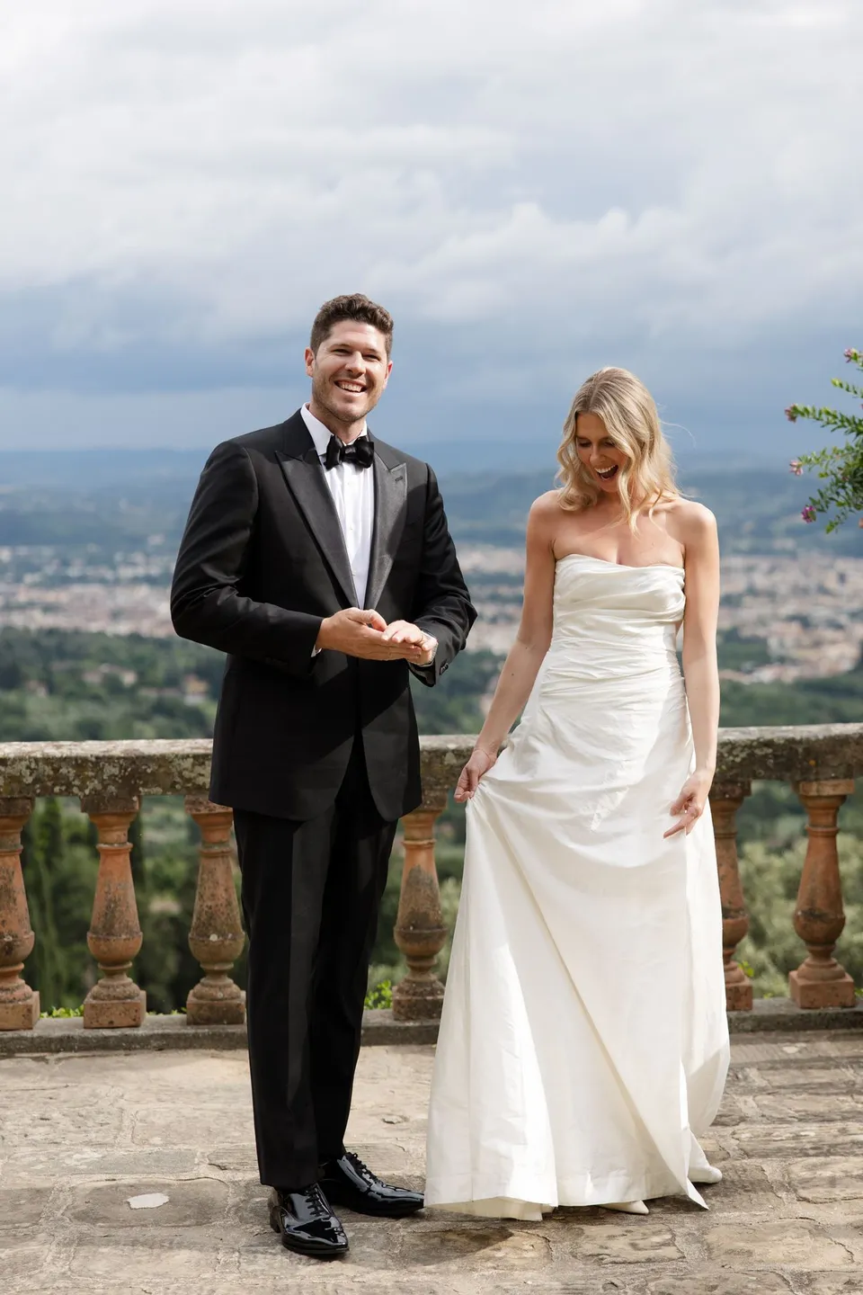 Holly and Matthew laughing together beside the terrace balustrade after their vows, at Villa San Michele in Fiesole above Florence, Tuscany, Italy, for an Elopement Collective elopement. Digital photograph by Khara from House of Lucie.