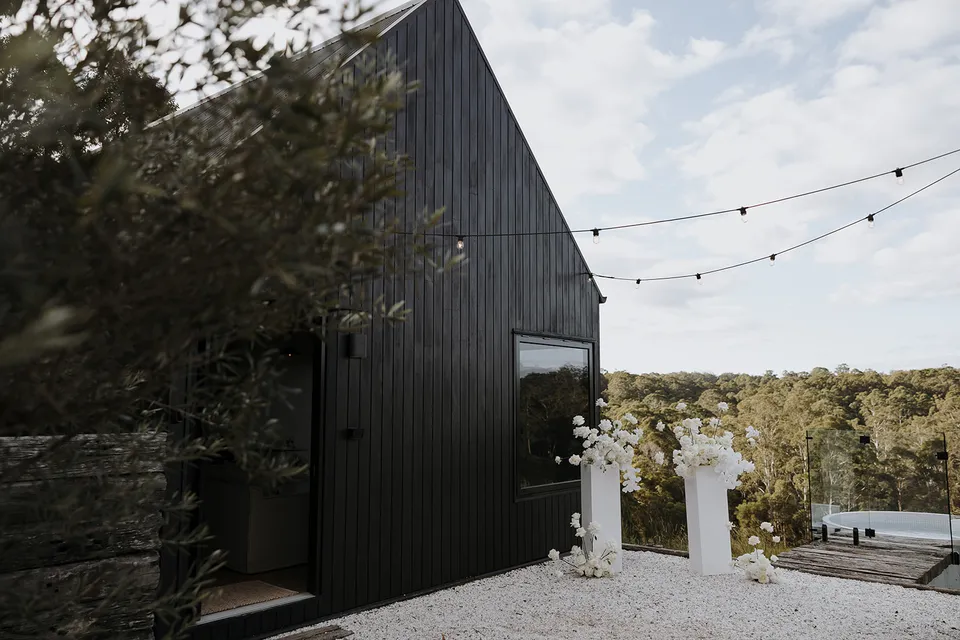 Roundhill Retreat’s dark cabin and white ceremony flowers overlooking the hills of Obi Obi for an Elopement Collective elopement in the Sunshine Coast Hinterland.