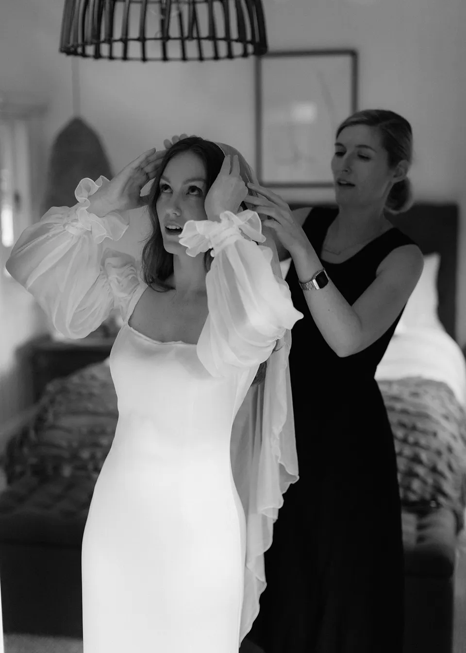 Black-and-white photograph of Elyse and her helper adjusting the veil. At Fig Tree Villa in Ewingsdale, Byron Bay, for an Elopement Collective elopement. Photograph by Bulb Creative.