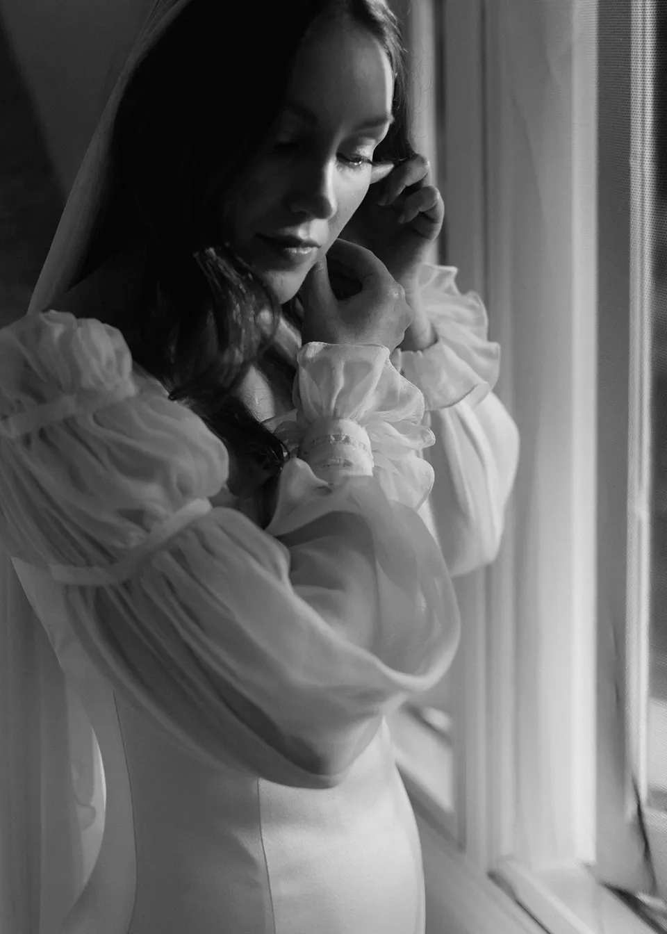 Black-and-white close portrait of Elyse in her veil by the window. At Fig Tree Villa in Ewingsdale, Byron Bay, for an Elopement Collective elopement. Photograph by Bulb Creative.