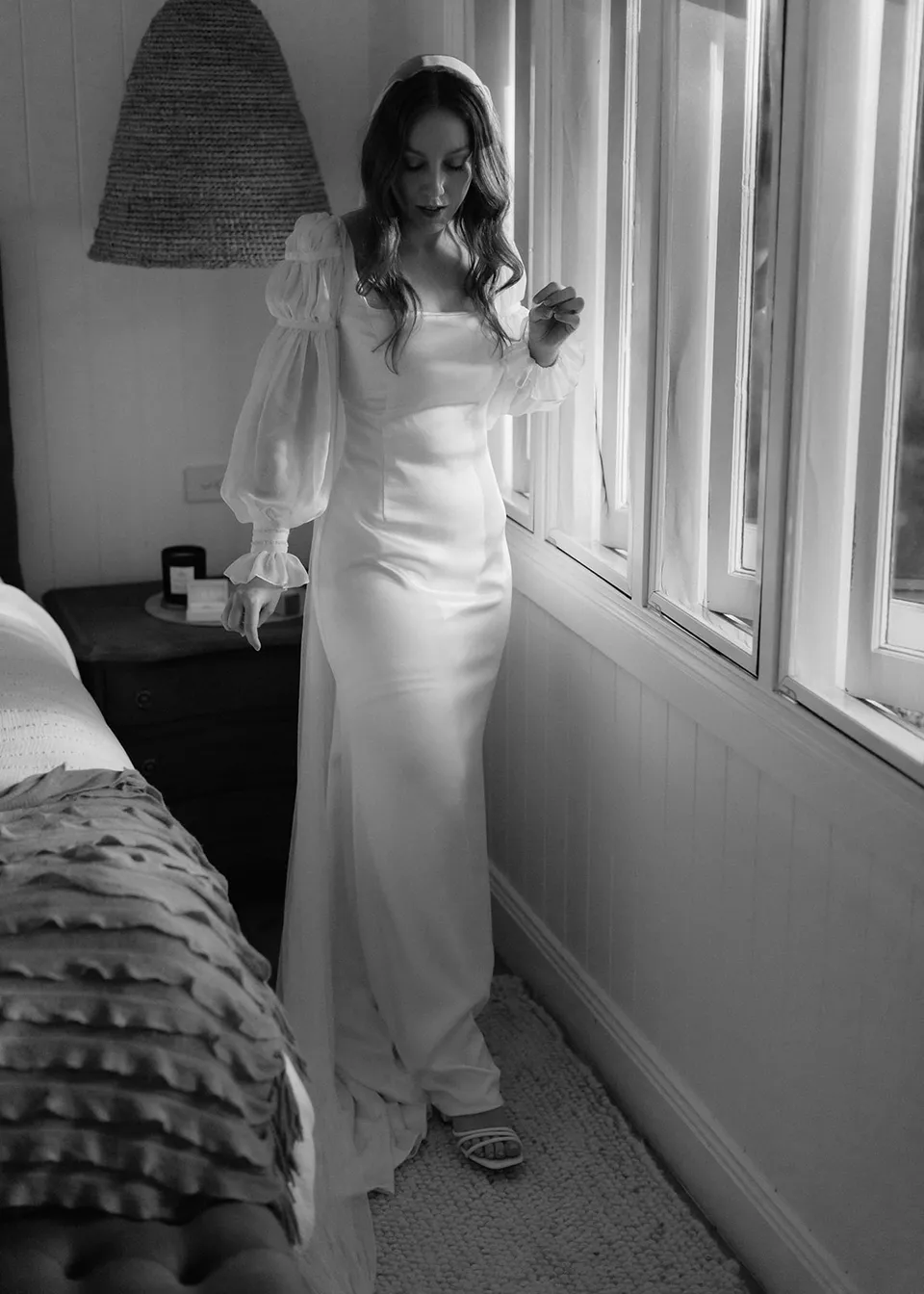 Black-and-white full-length portrait of Elyse in the bedroom. At Fig Tree Villa in Ewingsdale, Byron Bay, for an Elopement Collective elopement. Photograph by Bulb Creative.