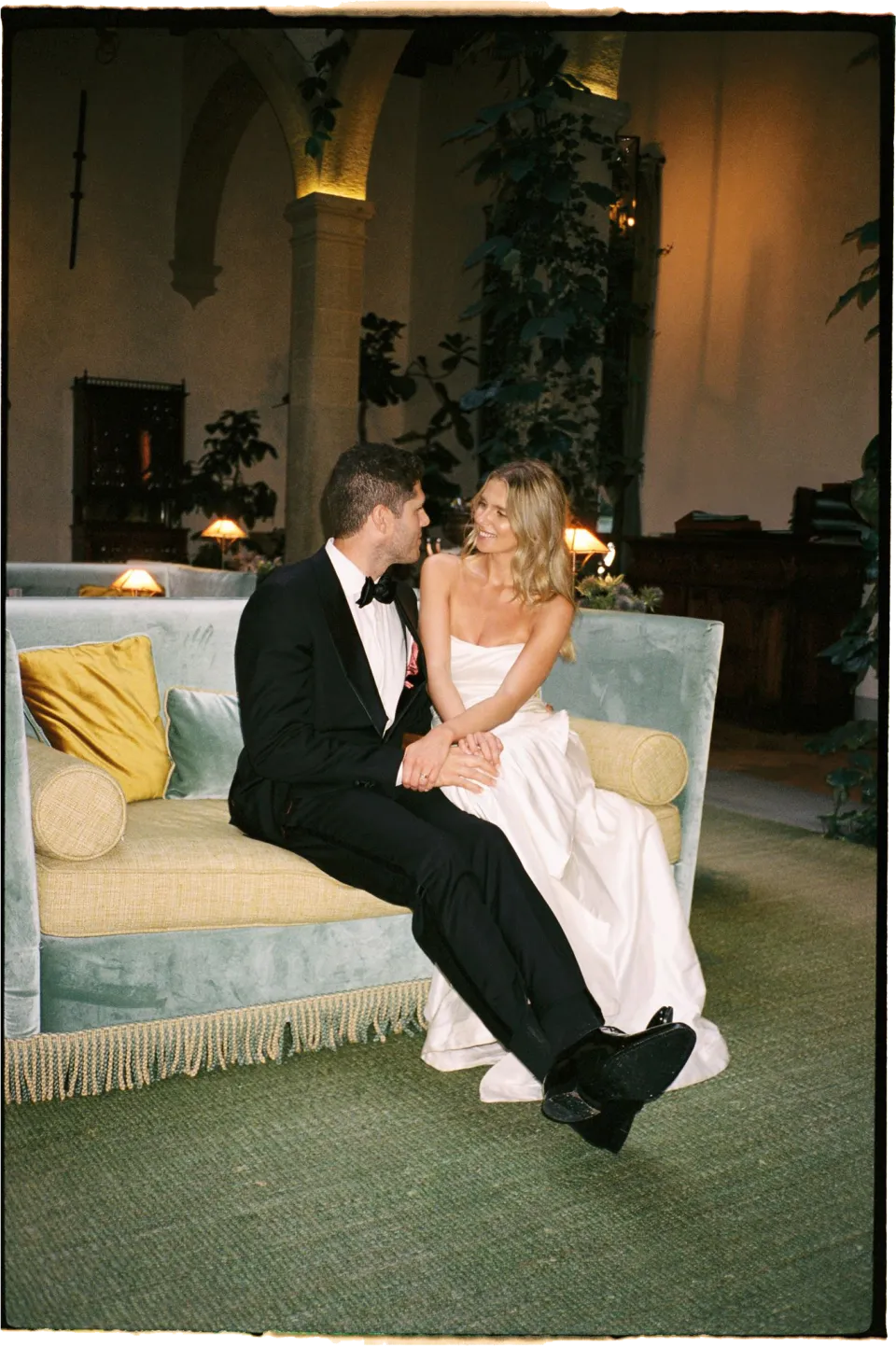 Holly and Matthew kissing as they sit on a sofa in the villa lounge, at Villa San Michele in Fiesole above Florence, Tuscany, Italy, for an Elopement Collective elopement. Film photograph by Khara from House of Lucie.