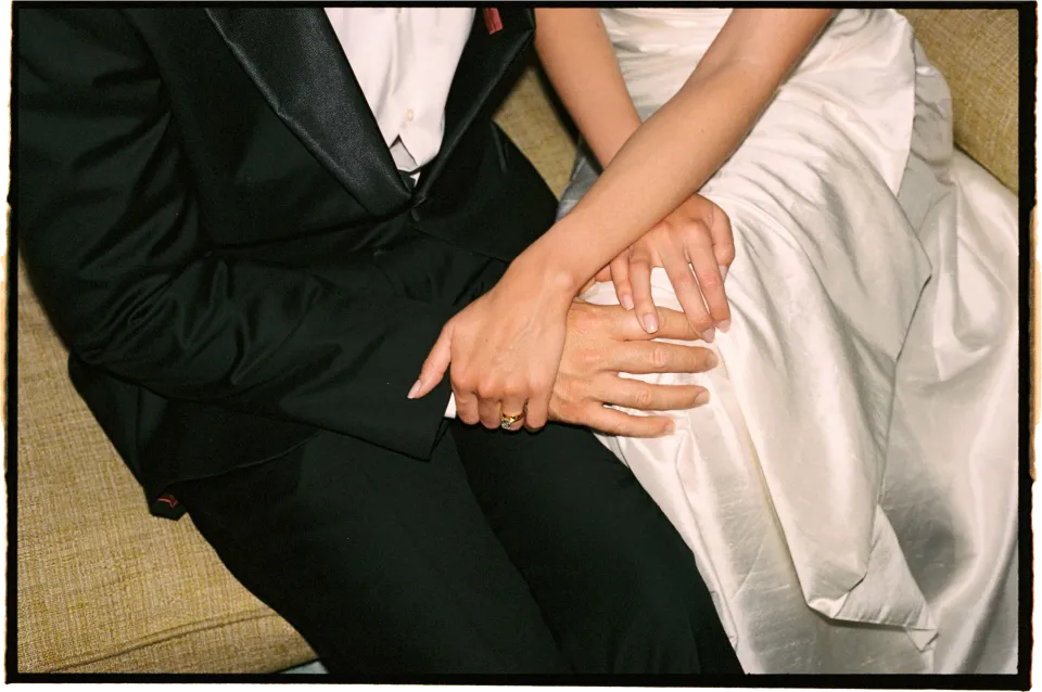 Close view of Holly and Matthew’s hands together on the sofa, with their wedding rings and the folds of her dress, at Villa San Michele in Fiesole above Florence, Tuscany, Italy, for an Elopement Collective elopement. Film photograph by Khara from House of Lucie.