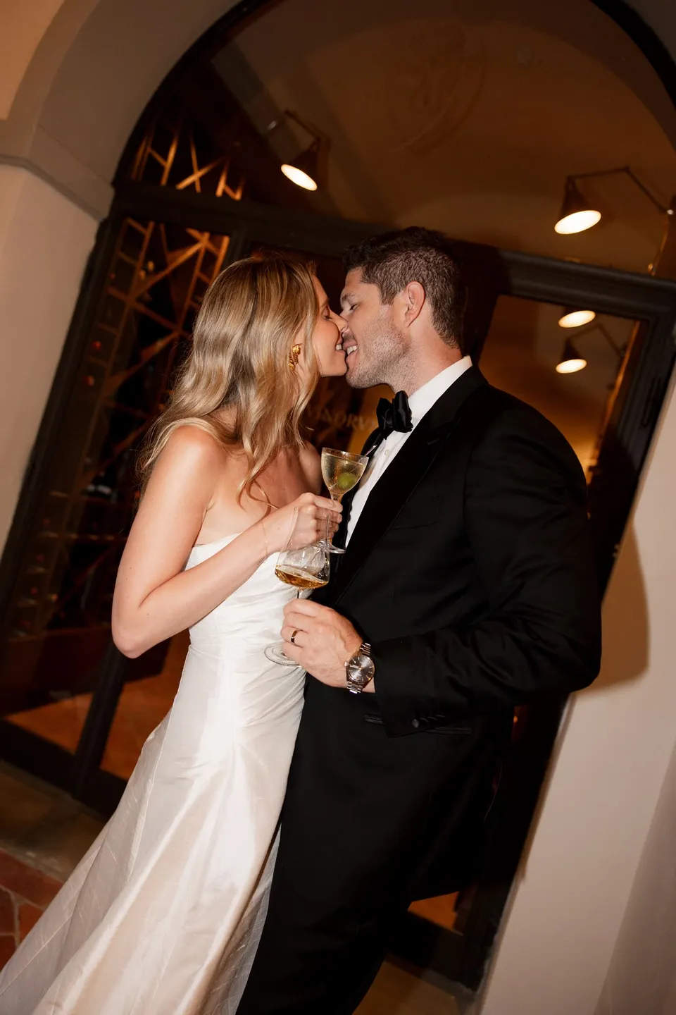 Holly and Matthew kissing while holding their wine glasses inside the villa, at Villa San Michele in Fiesole above Florence, Tuscany, Italy, for an Elopement Collective elopement. Digital photograph by Khara from House of Lucie.