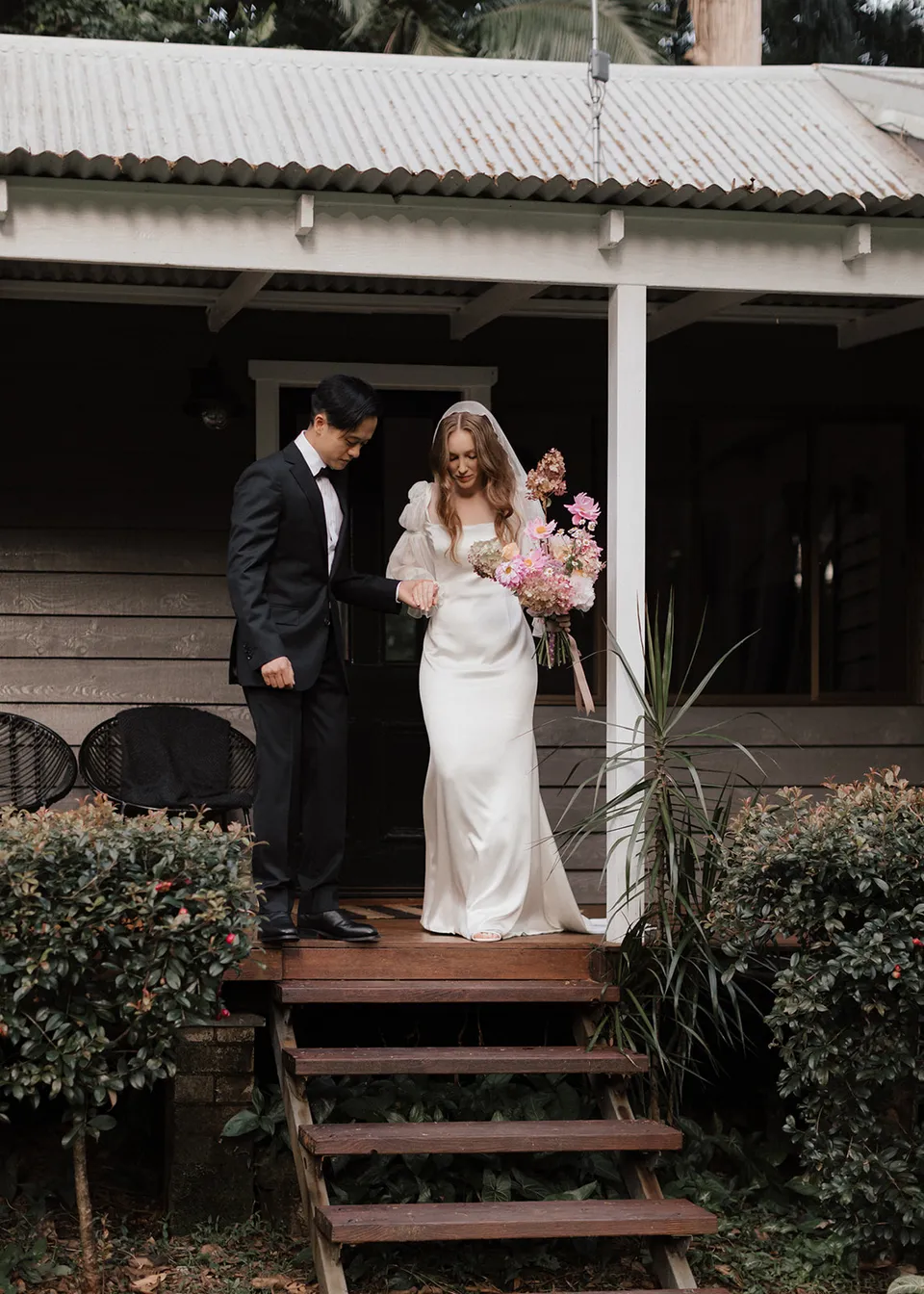 Elyse and Jonathan beginning to walk down the verandah steps. At Fig Tree Villa in Ewingsdale, Byron Bay, for an Elopement Collective elopement. Photograph by Bulb Creative.