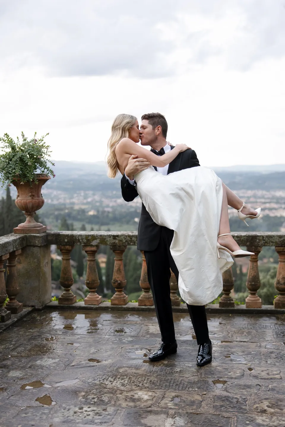 Matthew lifting Holly into his arms for a kiss on the terrace above Florence, at Villa San Michele in Fiesole above Florence, Tuscany, Italy, for an Elopement Collective elopement. Digital photograph by Khara from House of Lucie.