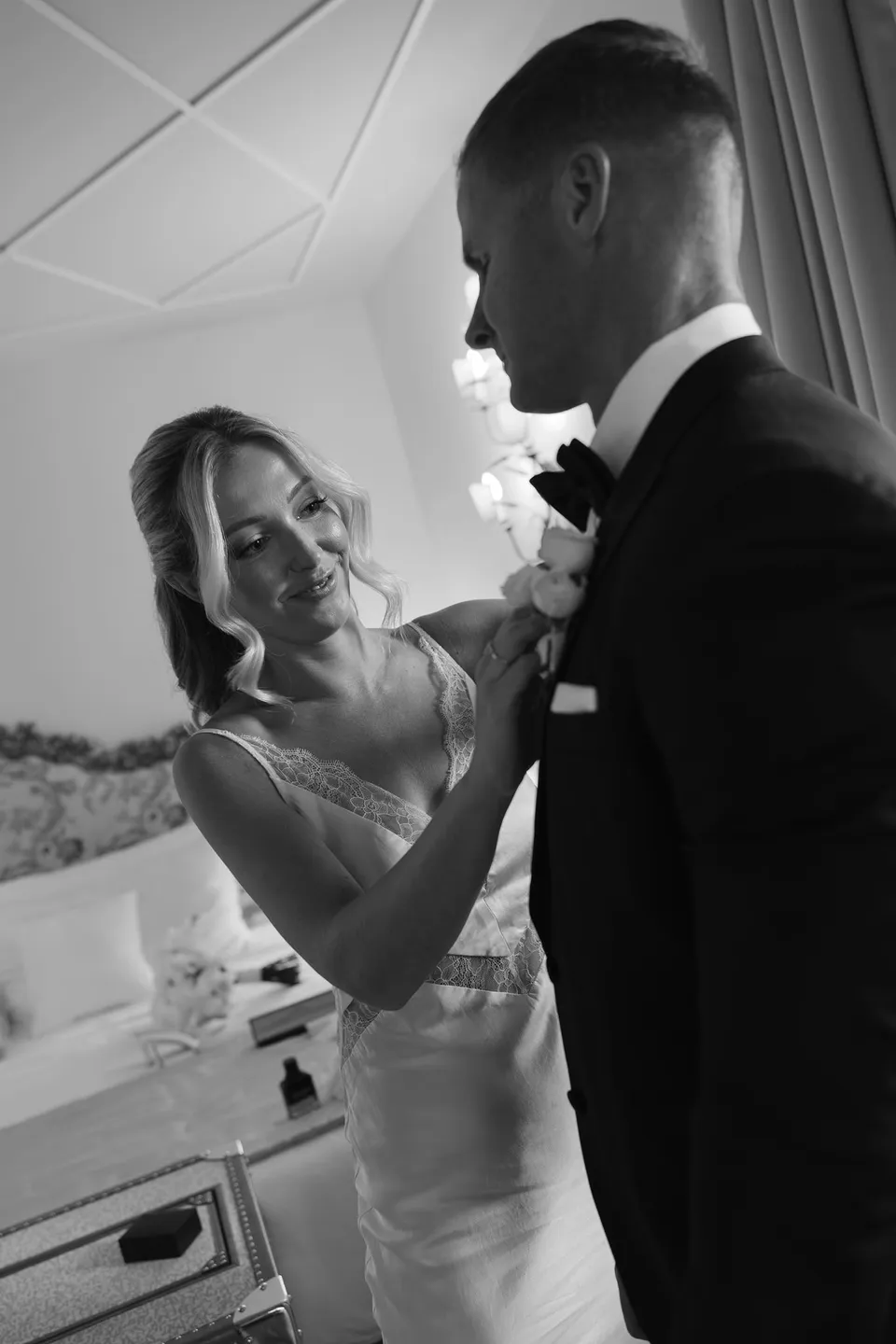 Black and white photograph of Zoe adjusting Charlton’s white floral boutonniere by Garden of Love as he looks down at her, at Passalacqua in Moltrasio, Lake Como, Italy, for an Elopement Collective elopement. Photo by George Bowden.