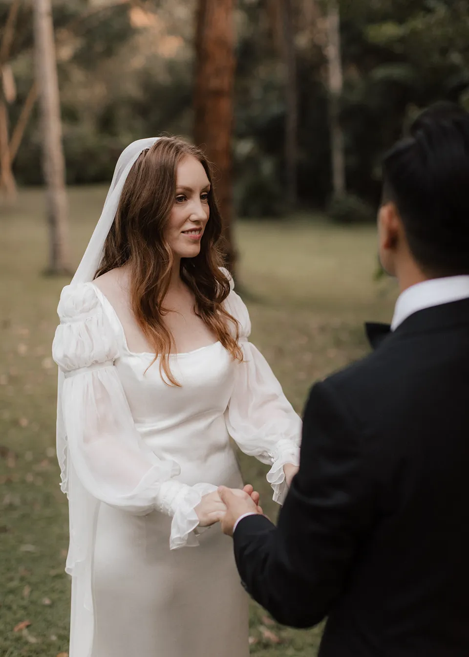 Elyse smiling at Jonathan during their garden ceremony. At Fig Tree Villa in Ewingsdale, Byron Bay, for an Elopement Collective elopement. Photograph by Bulb Creative.