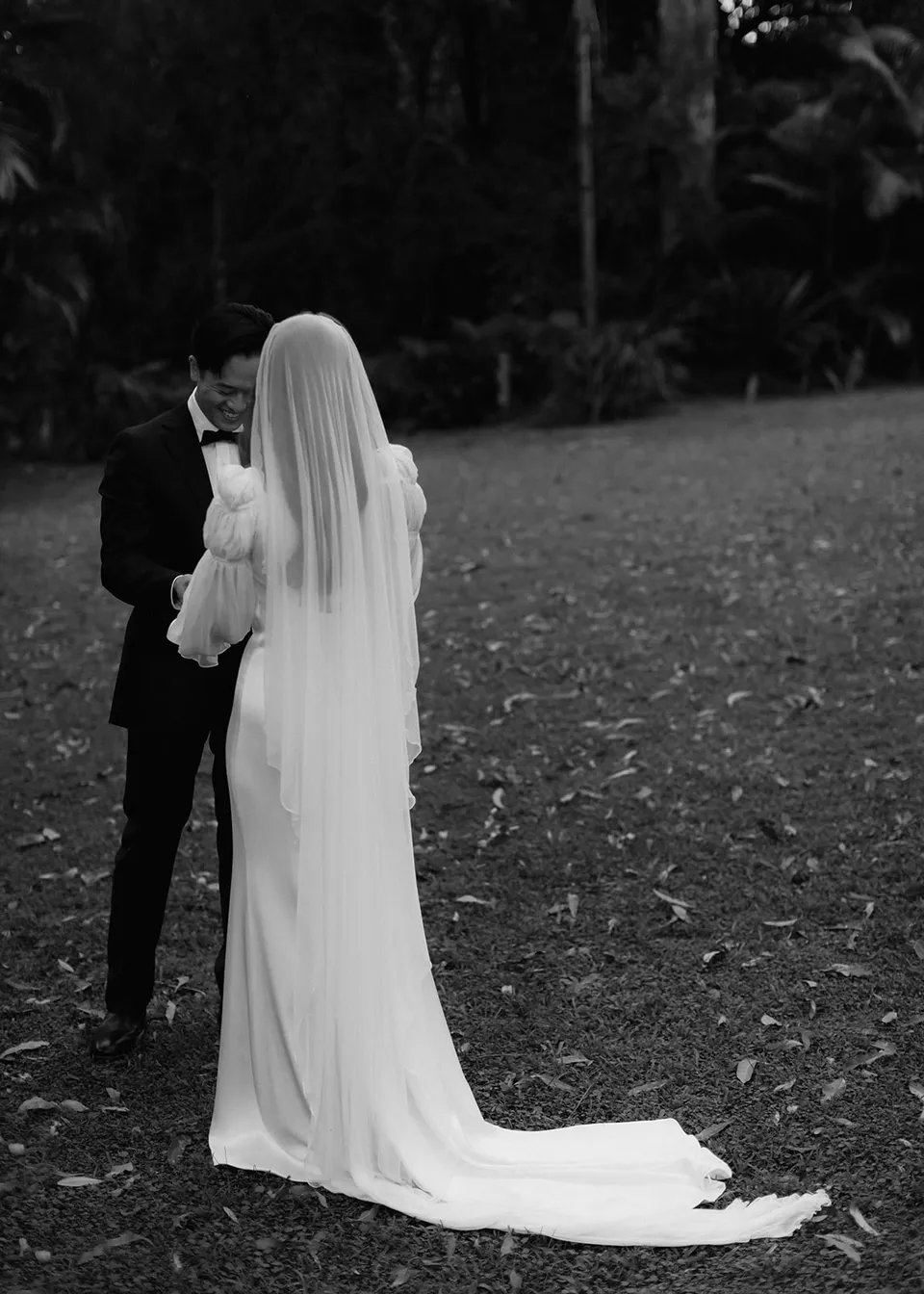 Black-and-white rear view of Elyse's long veil during the ceremony. At Fig Tree Villa in Ewingsdale, Byron Bay, for an Elopement Collective elopement. Photograph by Bulb Creative.