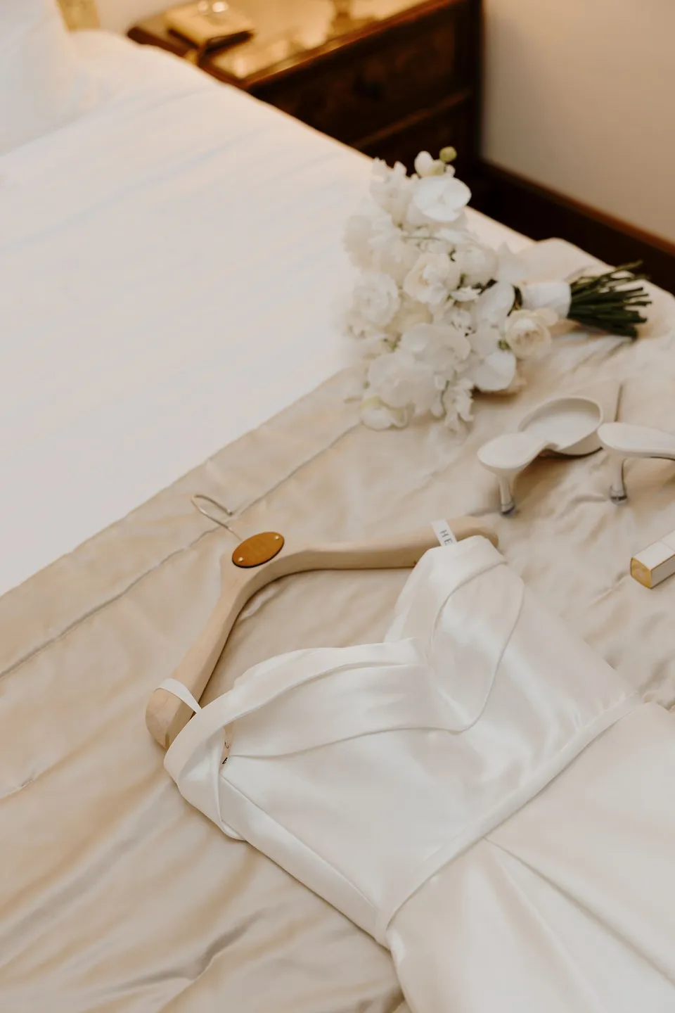 Zoe’s white dress, white bouquet by Garden of Love and bridal accessories laid out on a bed, at Passalacqua in Moltrasio, Lake Como, Italy, for an Elopement Collective elopement. Photo by George Bowden.