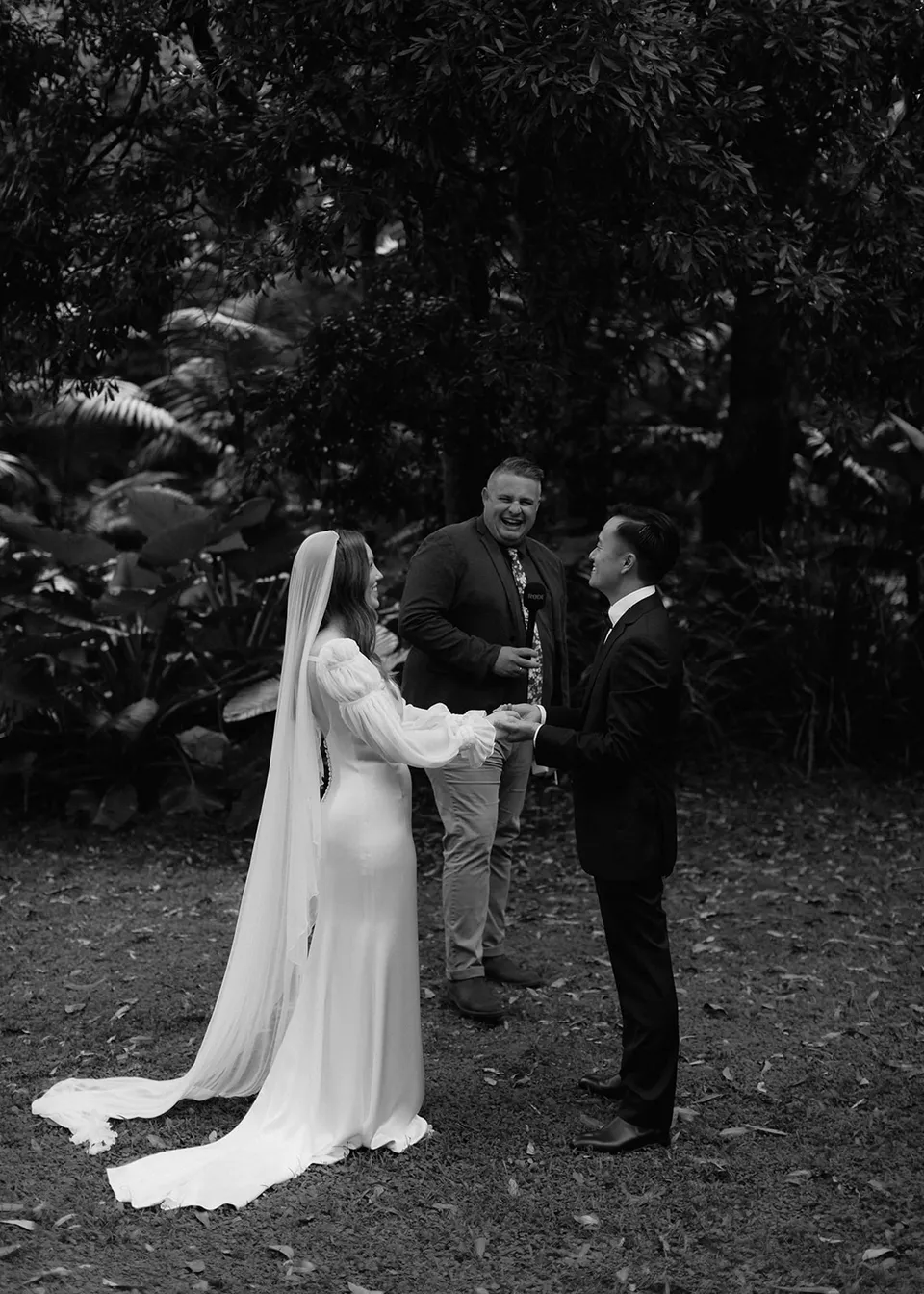 Black-and-white portrait of the couple holding hands during the ceremony. At Fig Tree Villa in Ewingsdale, Byron Bay, for an Elopement Collective elopement. Photograph by Bulb Creative.