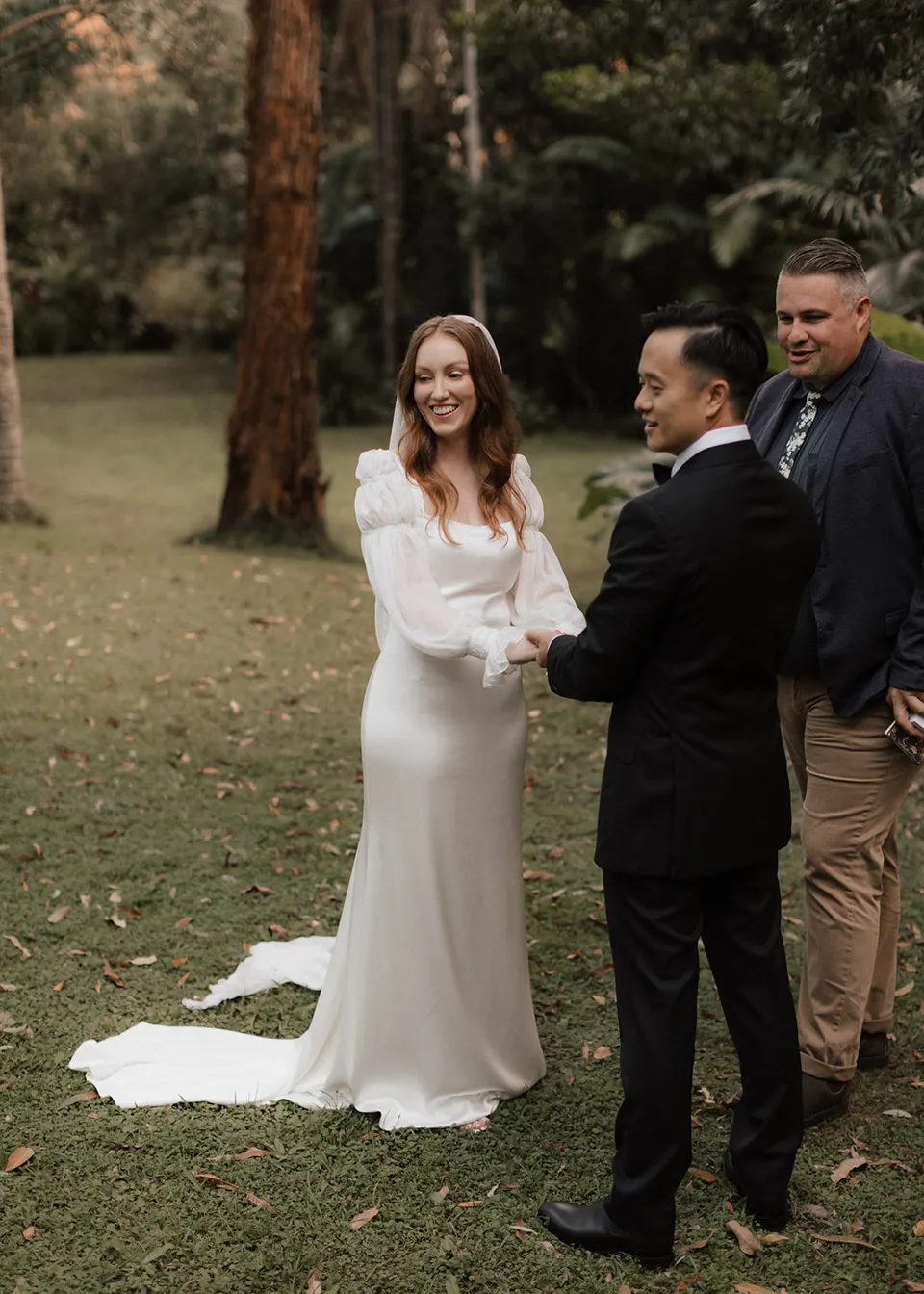 Elyse laughing during the ceremony as Jonathan holds her hands. At Fig Tree Villa in Ewingsdale, Byron Bay, for an Elopement Collective elopement. Photograph by Bulb Creative.