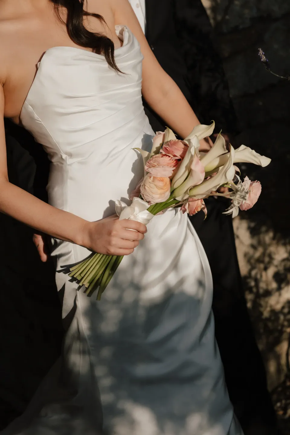 Dani holding her peach and cream bouquet by The Romantics against her white dress, at Thalia Haven on Tasmania’s east coast, for an Elopement Collective elopement. Photograph by Bulb Creative.