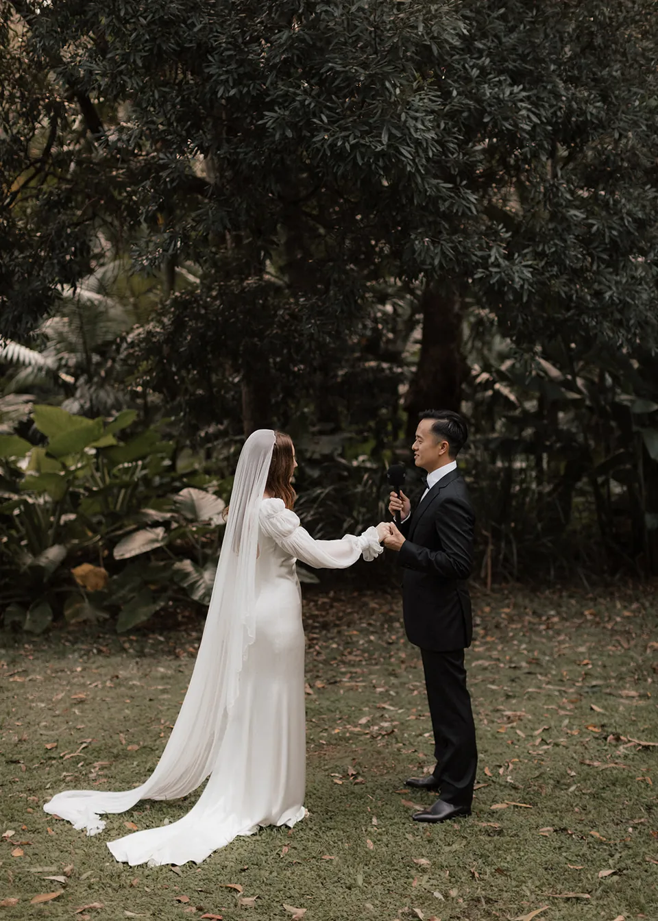 Wide portrait of Jonathan speaking his vows to Elyse in the garden. At Fig Tree Villa in Ewingsdale, Byron Bay, for an Elopement Collective elopement. Photograph by Bulb Creative.