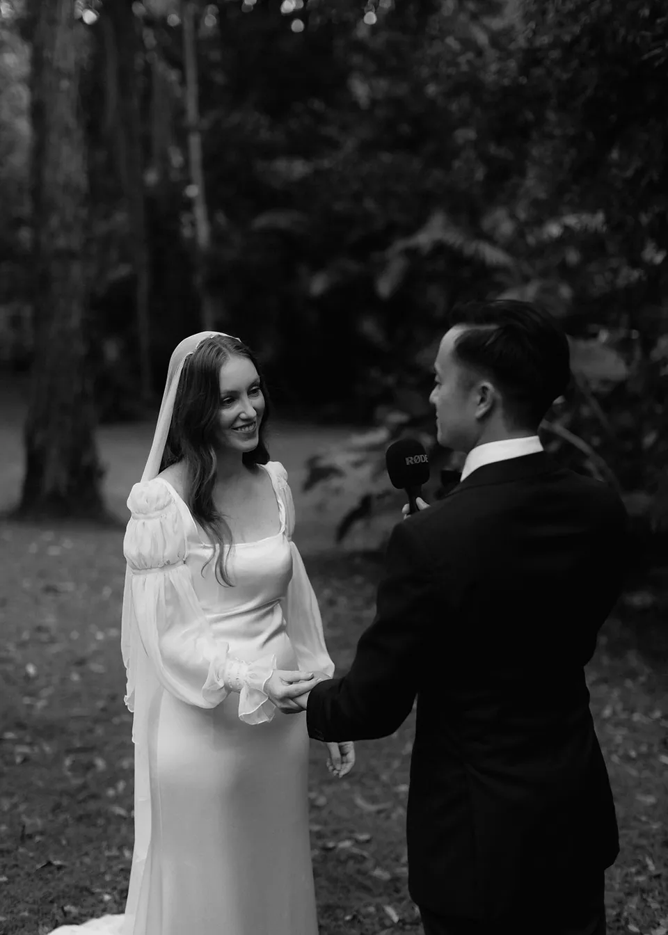 Black-and-white photograph of Jonathan speaking as Elyse listens. At Fig Tree Villa in Ewingsdale, Byron Bay, for an Elopement Collective elopement. Photograph by Bulb Creative.