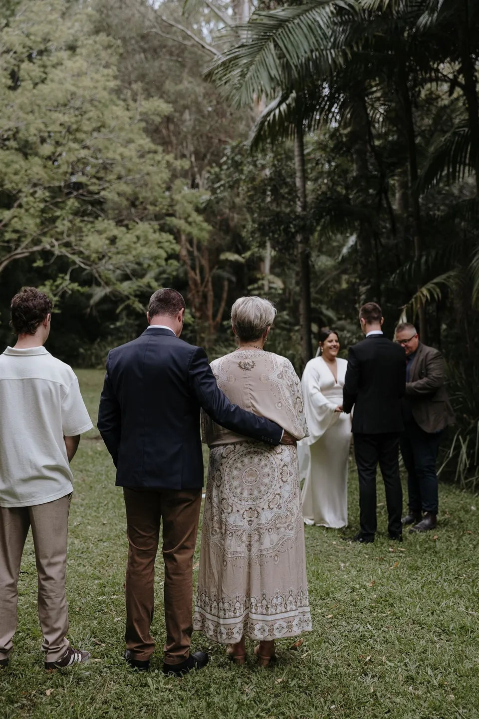 A small group of guests watching Laura and Matthew's garden ceremony. At Fig Tree Villa in Ewingsdale, Byron Bay, for an Elopement Collective elopement. Photograph by George Bowden.
