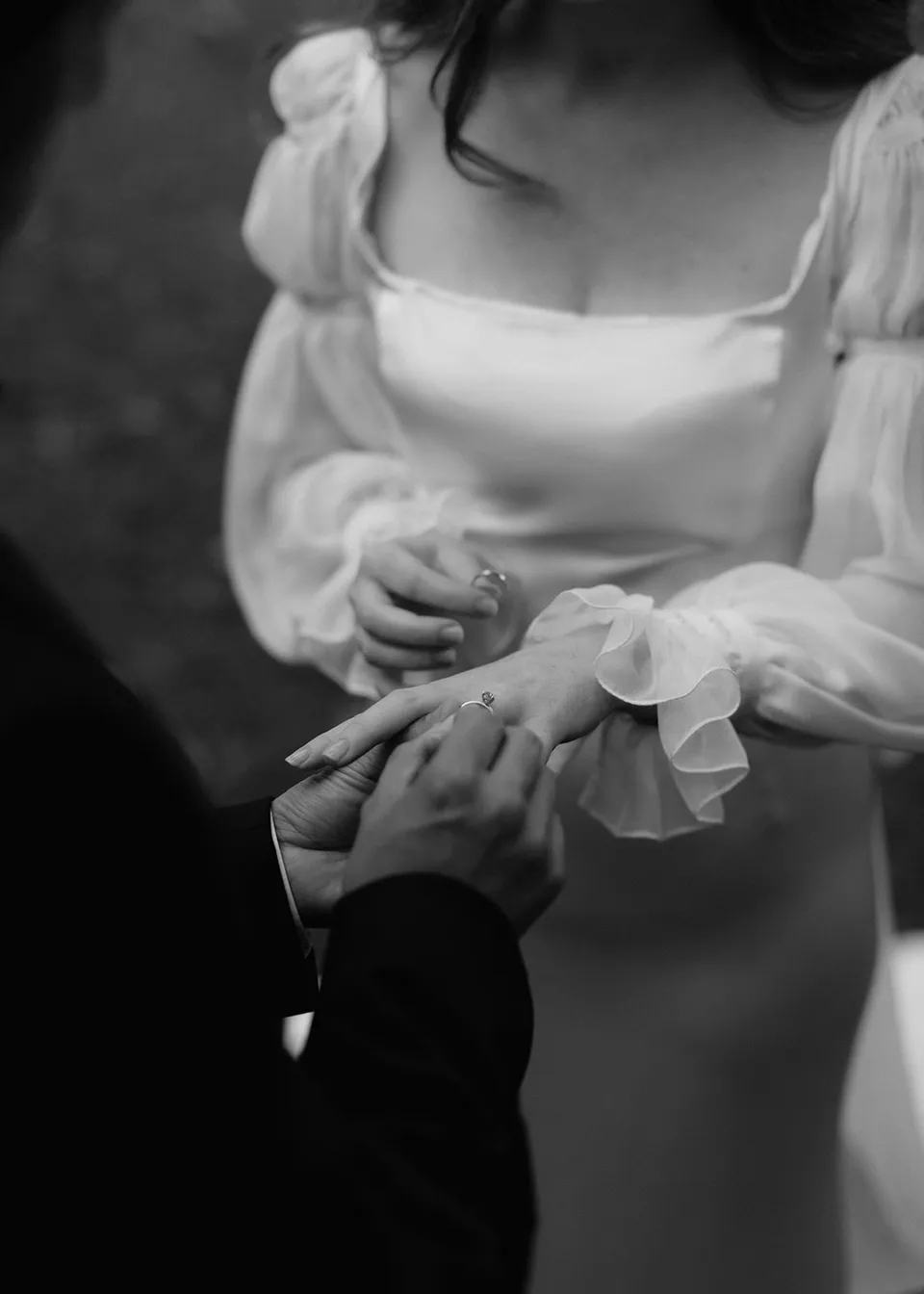 Black-and-white detail of the couple's hands during the ring exchange. At Fig Tree Villa in Ewingsdale, Byron Bay, for an Elopement Collective elopement. Photograph by Bulb Creative.