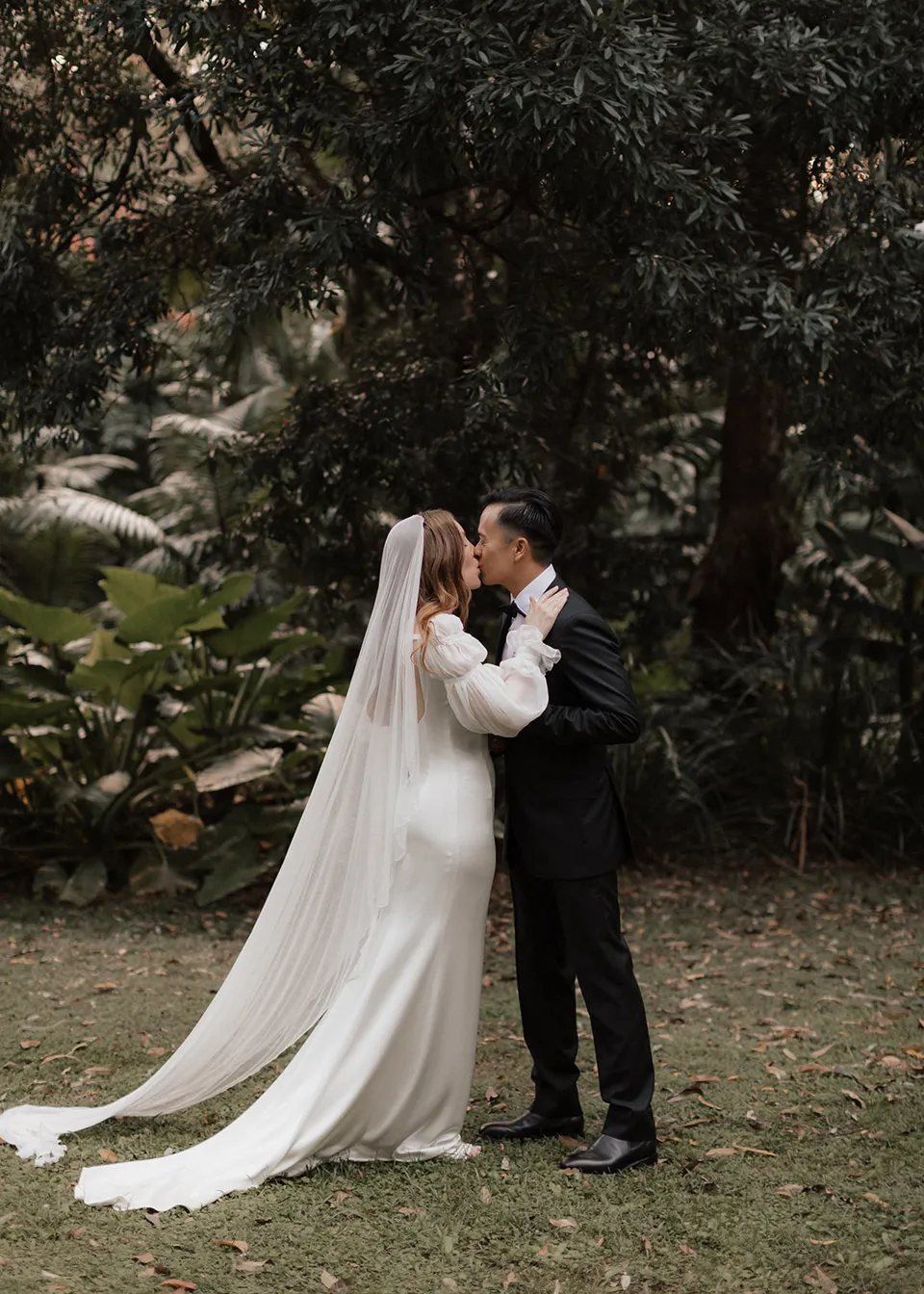 Elyse and Jonathan sharing their first kiss beneath the trees. At Fig Tree Villa in Ewingsdale, Byron Bay, for an Elopement Collective elopement. Photograph by Bulb Creative.