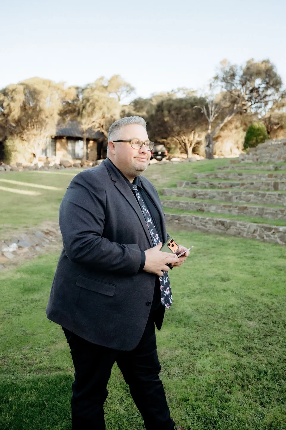 Celebrant Josh Withers holding his ceremony notes on the grass in Piermont’s amphitheatre. At Piermont Retreat on Tasmania’s east coast, for an Elopement Collective elopement. Photograph by Omar of By The Wilde.