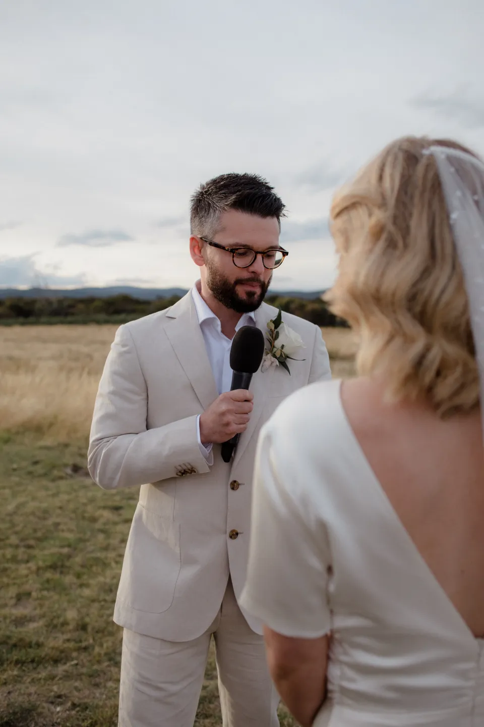 Jack smiling as he speaks into the microphone during his vows, at Thalia Haven on the East Coast of Tasmania, Australia, for an Elopement Collective elopement. Photograph by Joey Willis.