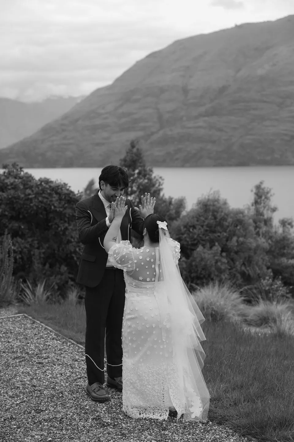 Jaeda and Adrian facing each other outside their alpine accommodation during their first look, in black and white, at their alpine Airbnb in Ben Lomond, Queenstown, New Zealand, for an Elopement Collective Queenstown elopement. Photograph by Bulb Creative.