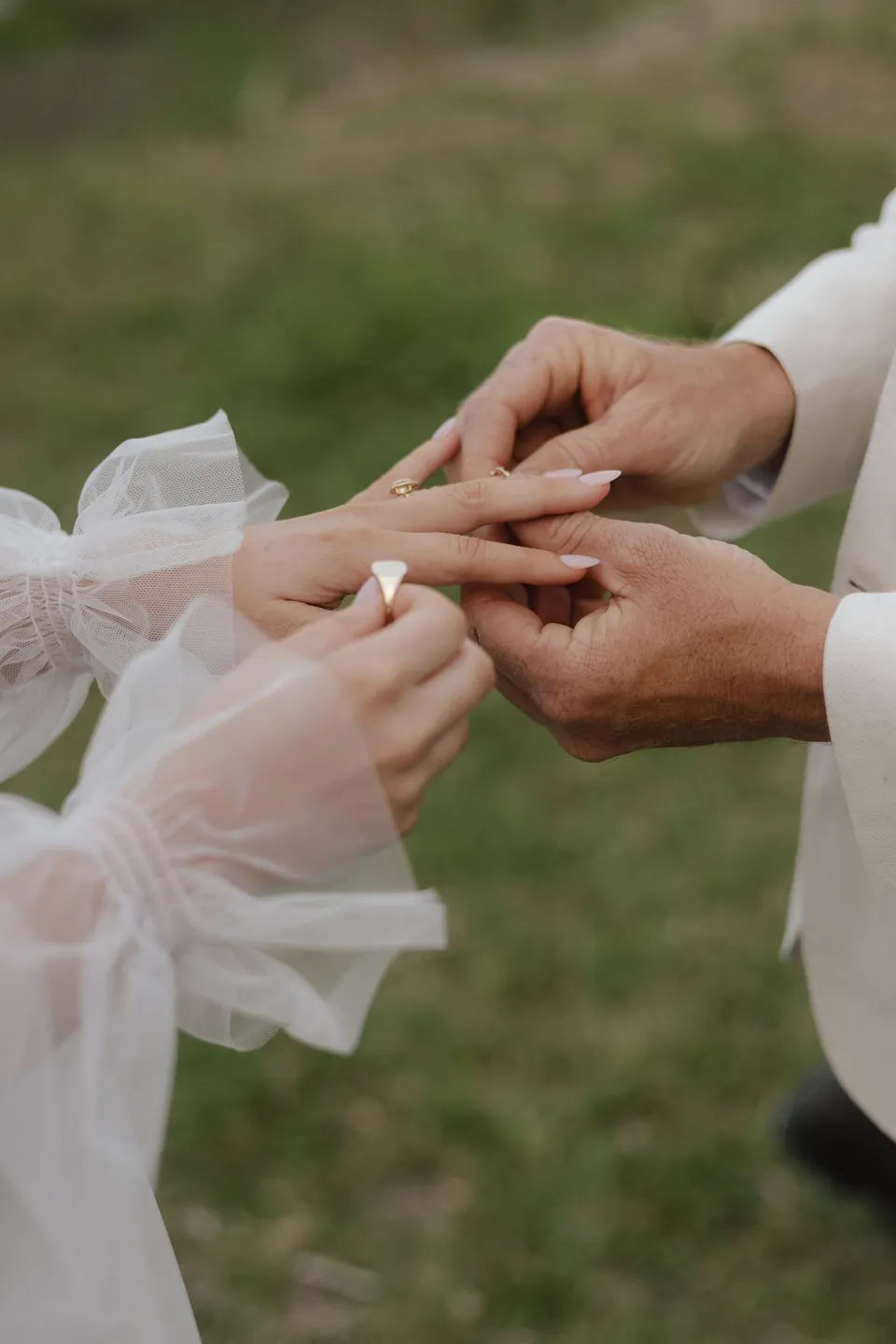 Close-up of a wedding ring being placed on a finger during Bridget and James's ceremony. At Cudgera Creek in northern New South Wales, for an Elopement Collective elopement. Photograph by Bulb Creative.