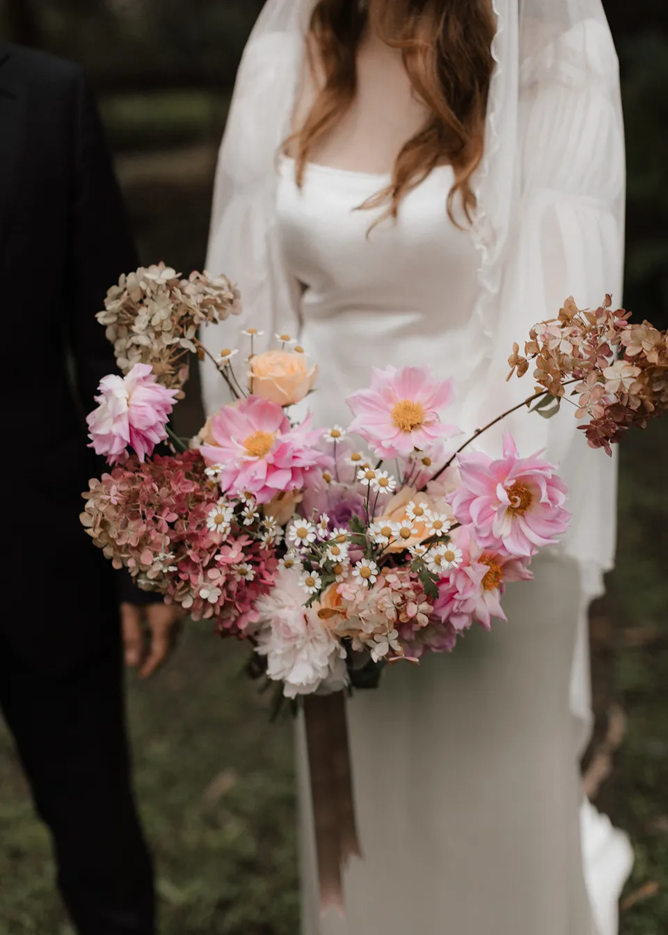 Close-up of Elyse's pink and cream bouquet against her wedding dress, with flowers by The Perfect Party Co. At Fig Tree Villa in Ewingsdale, Byron Bay, for an Elopement Collective elopement. Photograph by Bulb Creative.