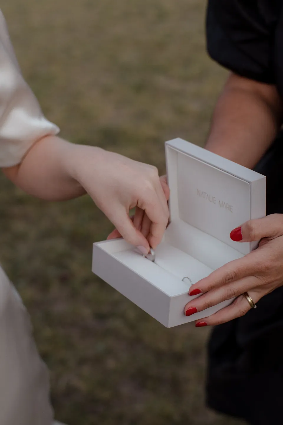 A close view of hands reaching into an open wedding ring box, at Thalia Haven on the East Coast of Tasmania, Australia, for an Elopement Collective elopement. Photograph by Joey Willis.