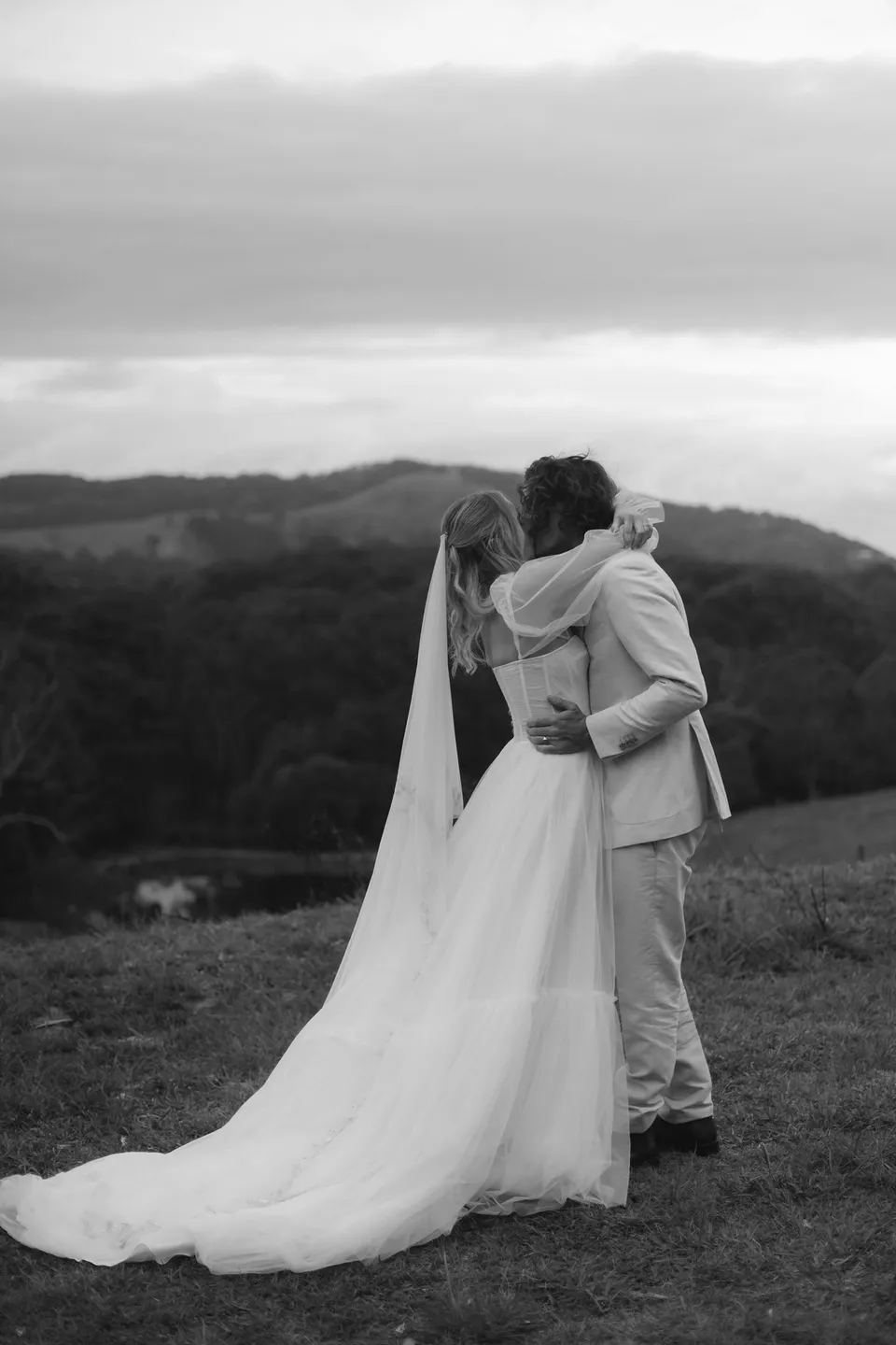 Black-and-white photograph of Bridget and James kissing after their vows. At Cudgera Creek in northern New South Wales, for an Elopement Collective elopement. Photograph by Bulb Creative.