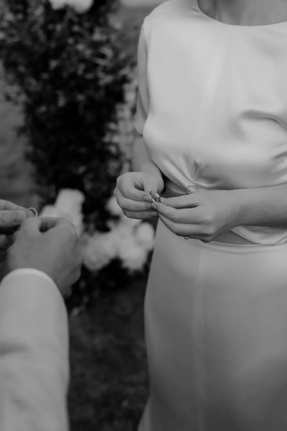 Black and white close-up of the couple’s hands during the ring exchange, at Thalia Haven on the East Coast of Tasmania, Australia, for an Elopement Collective elopement. Photograph by Joey Willis.