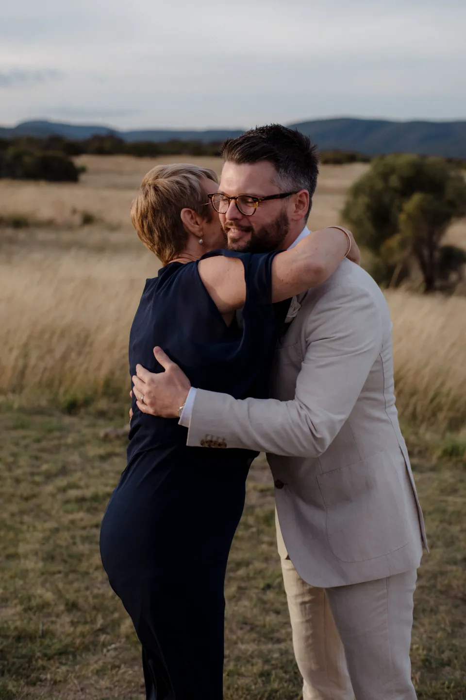 Jack embracing a loved one on the coastal lawn, at Thalia Haven on the East Coast of Tasmania, Australia, for an Elopement Collective elopement. Photograph by Joey Willis.