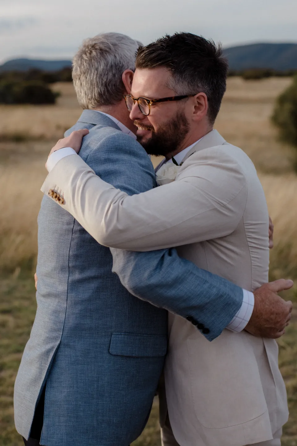 Jack hugging a loved one in a blue jacket, at Thalia Haven on the East Coast of Tasmania, Australia, for an Elopement Collective elopement. Photograph by Joey Willis.