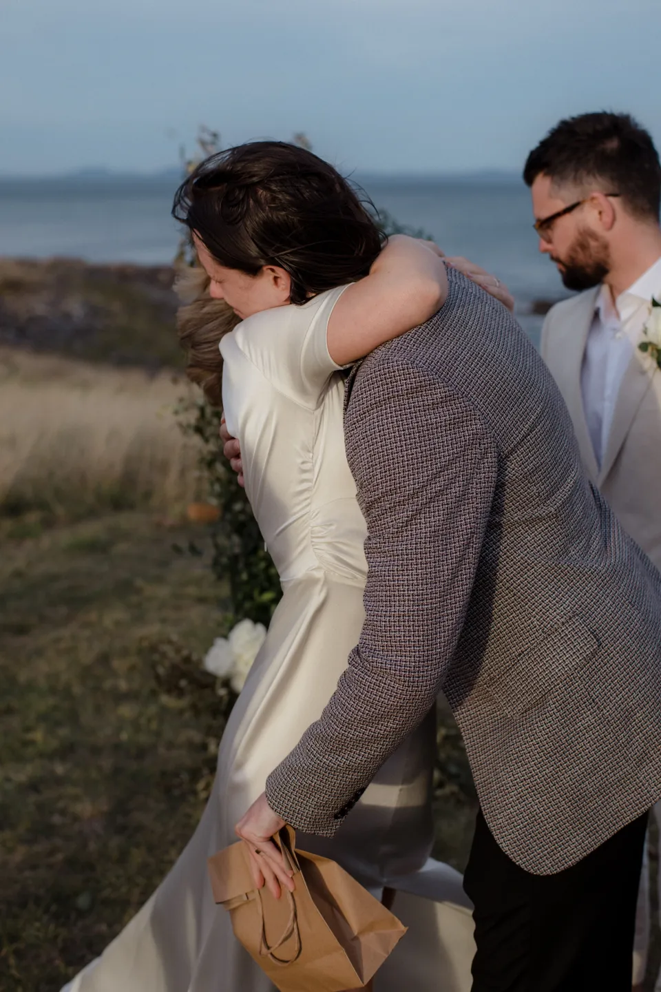 Loved ones sharing hugs after Jemmah and Jack’s ceremony, at Thalia Haven on the East Coast of Tasmania, Australia, for an Elopement Collective elopement. Photograph by Joey Willis.