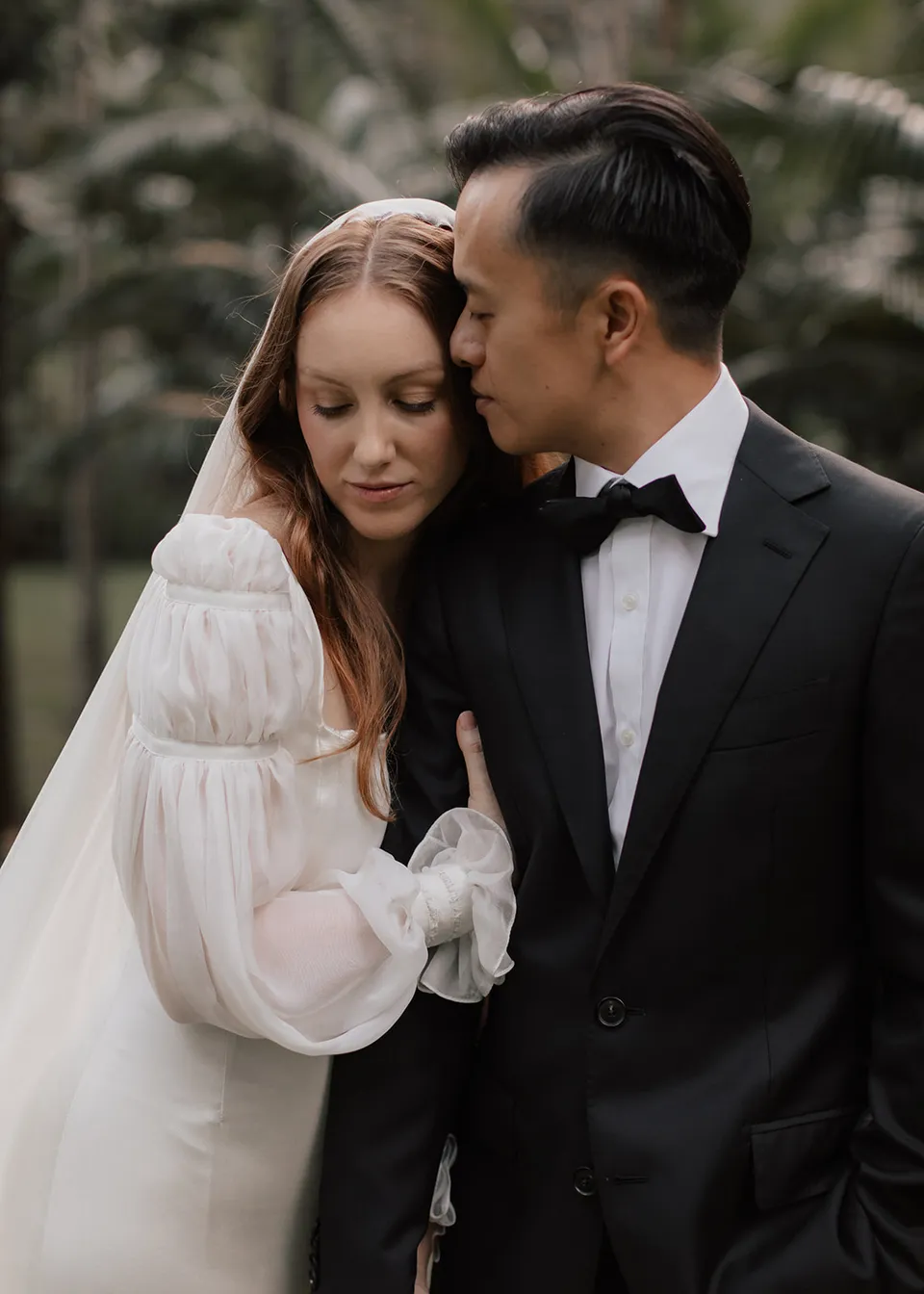 Jonathan kissing Elyse's forehead as she leans into him. At Fig Tree Villa in Ewingsdale, Byron Bay, for an Elopement Collective elopement. Photograph by Bulb Creative.