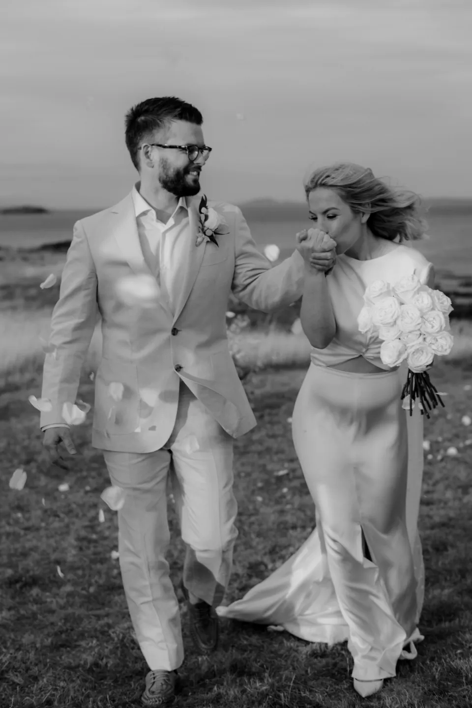 Black and white photograph of the newlyweds walking together after the ceremony, at Thalia Haven on the East Coast of Tasmania, Australia, for an Elopement Collective elopement. Photograph by Joey Willis.