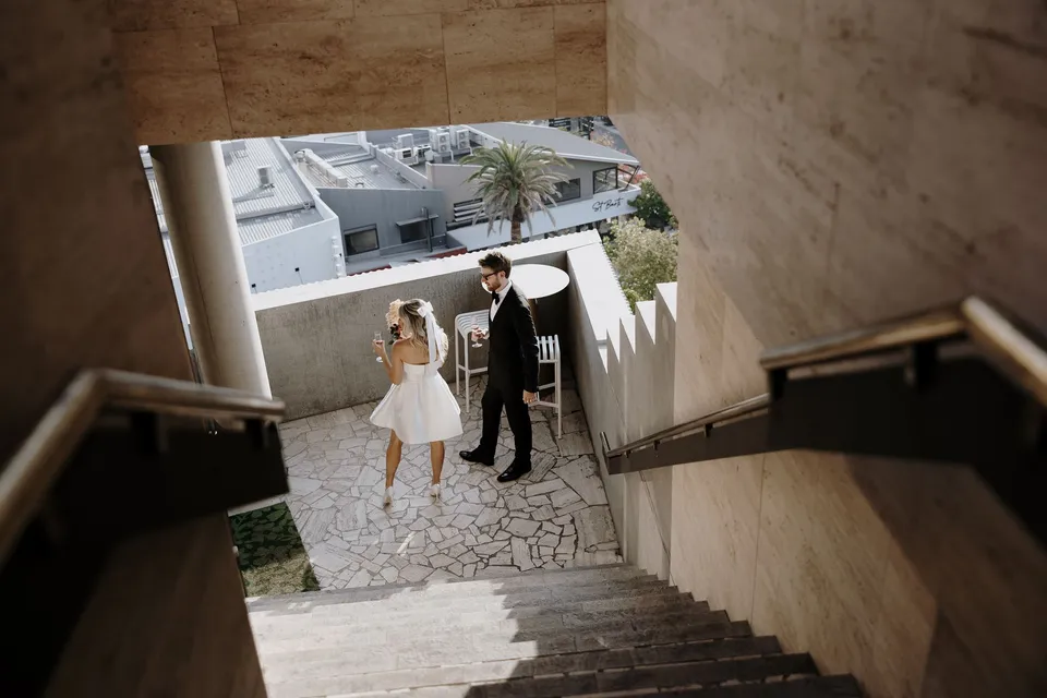 Danielle and Adam seen from above at the foot of a stone staircase, during Danielle and Adam’s Elopement Collective elopement at The Calile Hotel in Fortitude Valley, Brisbane.