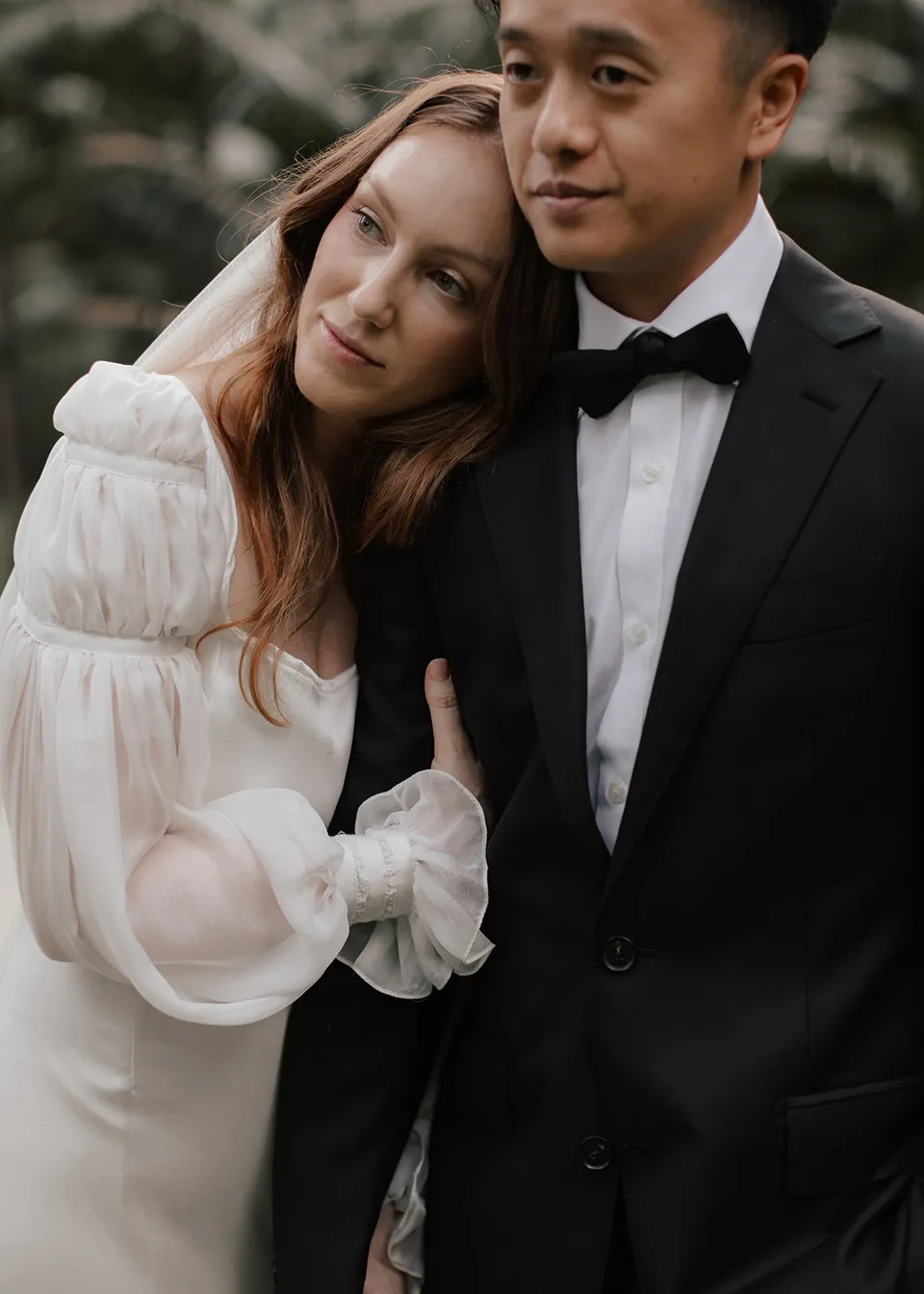 Elyse resting her head on Jonathan's shoulder beneath her veil. At Fig Tree Villa in Ewingsdale, Byron Bay, for an Elopement Collective elopement. Photograph by Bulb Creative.