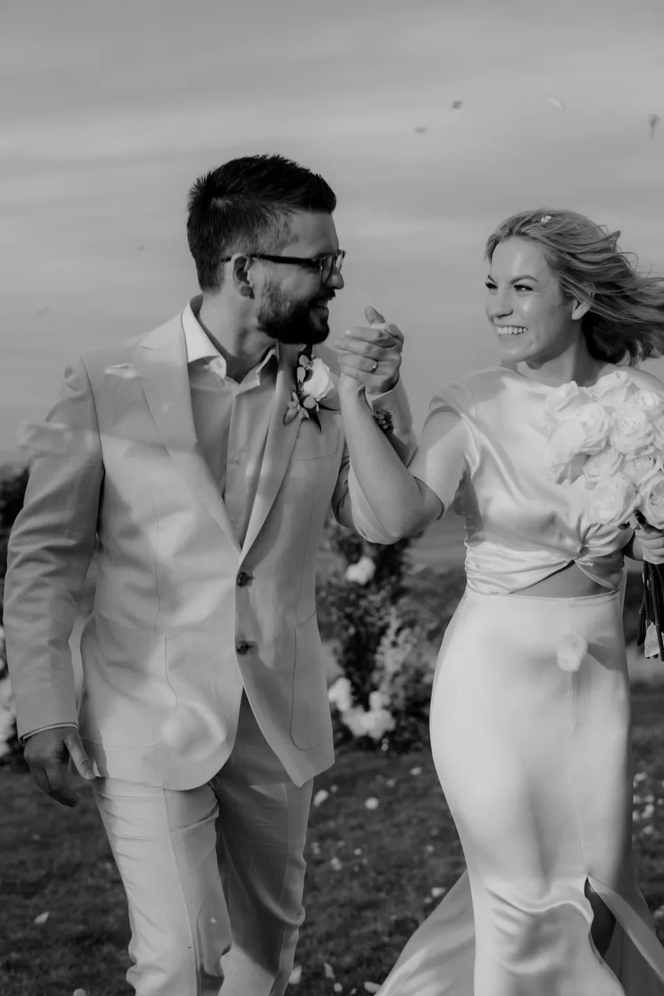Black and white photograph of Jack and Jemmah laughing as they walk, at Thalia Haven on the East Coast of Tasmania, Australia, for an Elopement Collective elopement. Photograph by Joey Willis.