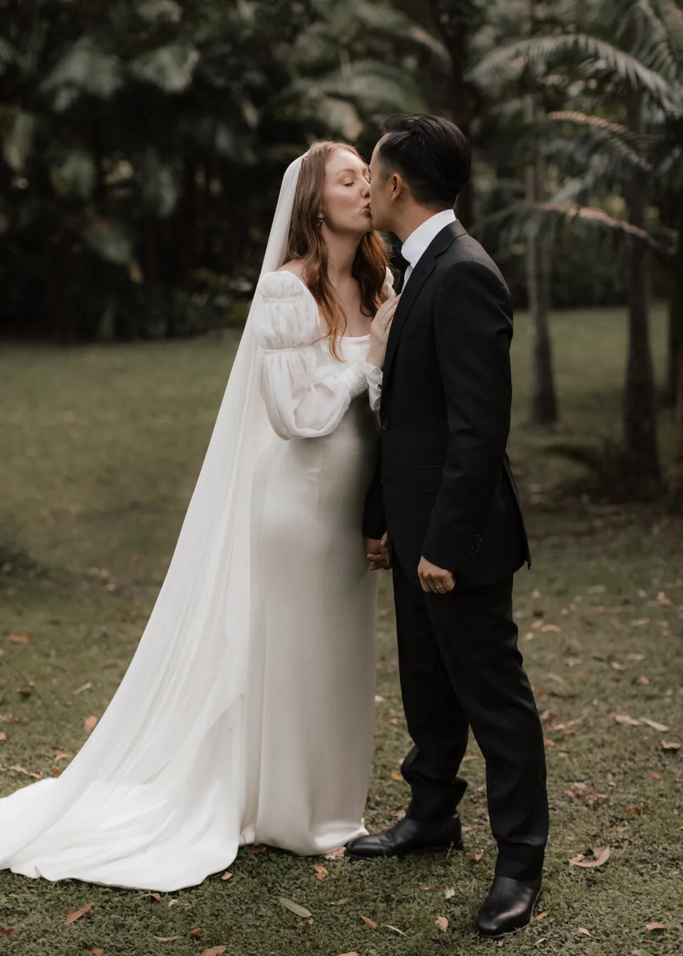Elyse and Jonathan kissing beneath the tree canopy. At Fig Tree Villa in Ewingsdale, Byron Bay, for an Elopement Collective elopement. Photograph by Bulb Creative.