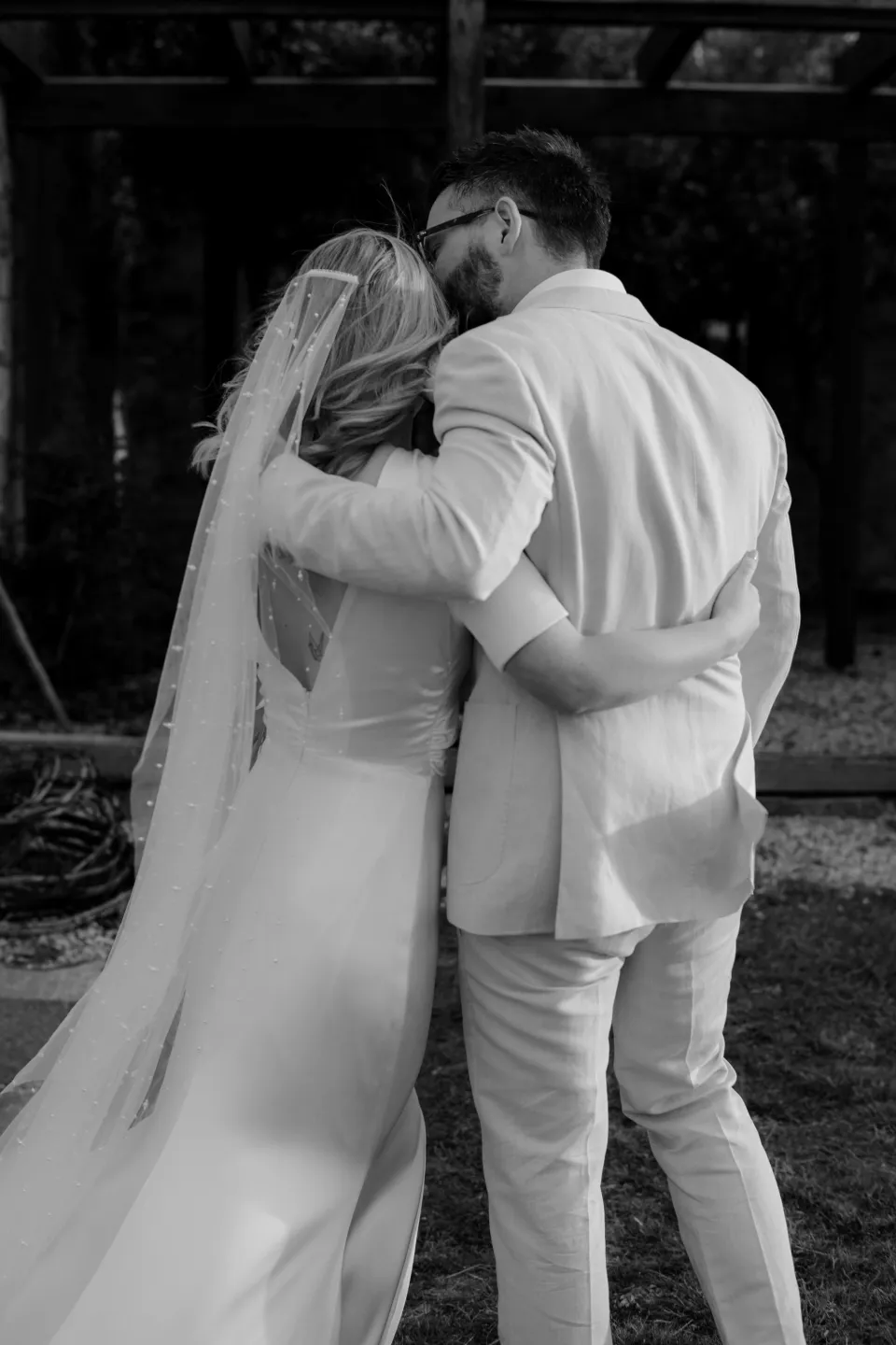 Black and white photograph of Jemmah and Jack kissing beside the house, at Thalia Haven on the East Coast of Tasmania, Australia, for an Elopement Collective elopement. Photograph by Joey Willis.